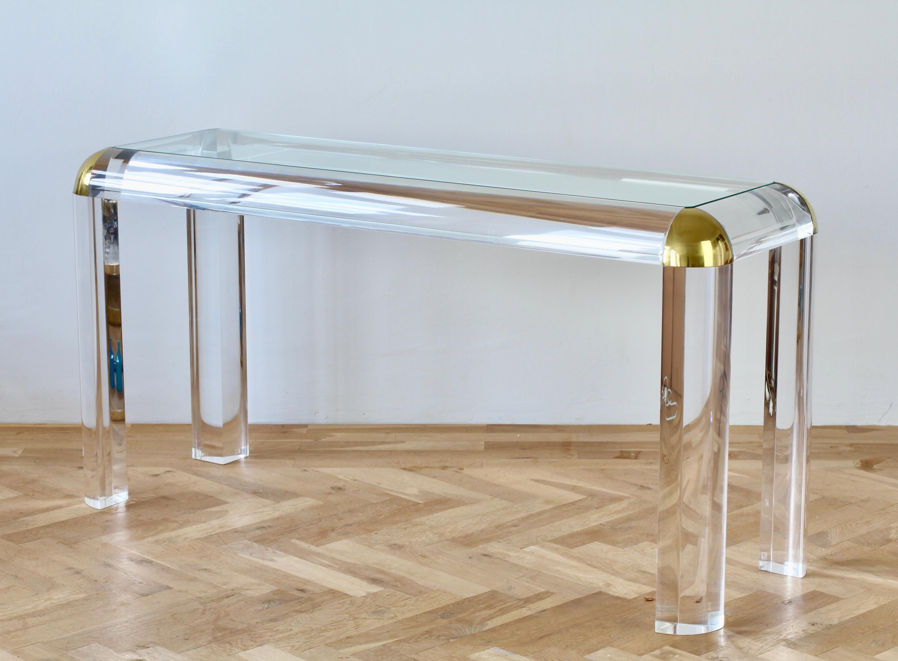 Refurbished vintage Mid-Century Modern Karl Springer style huge five foot long (150cm) and tall console, sofa, foyer or entrance table made of Lucite / acrylic with glass tabletop with brass trim and angled corners, circa 1980s. The heavy and thick