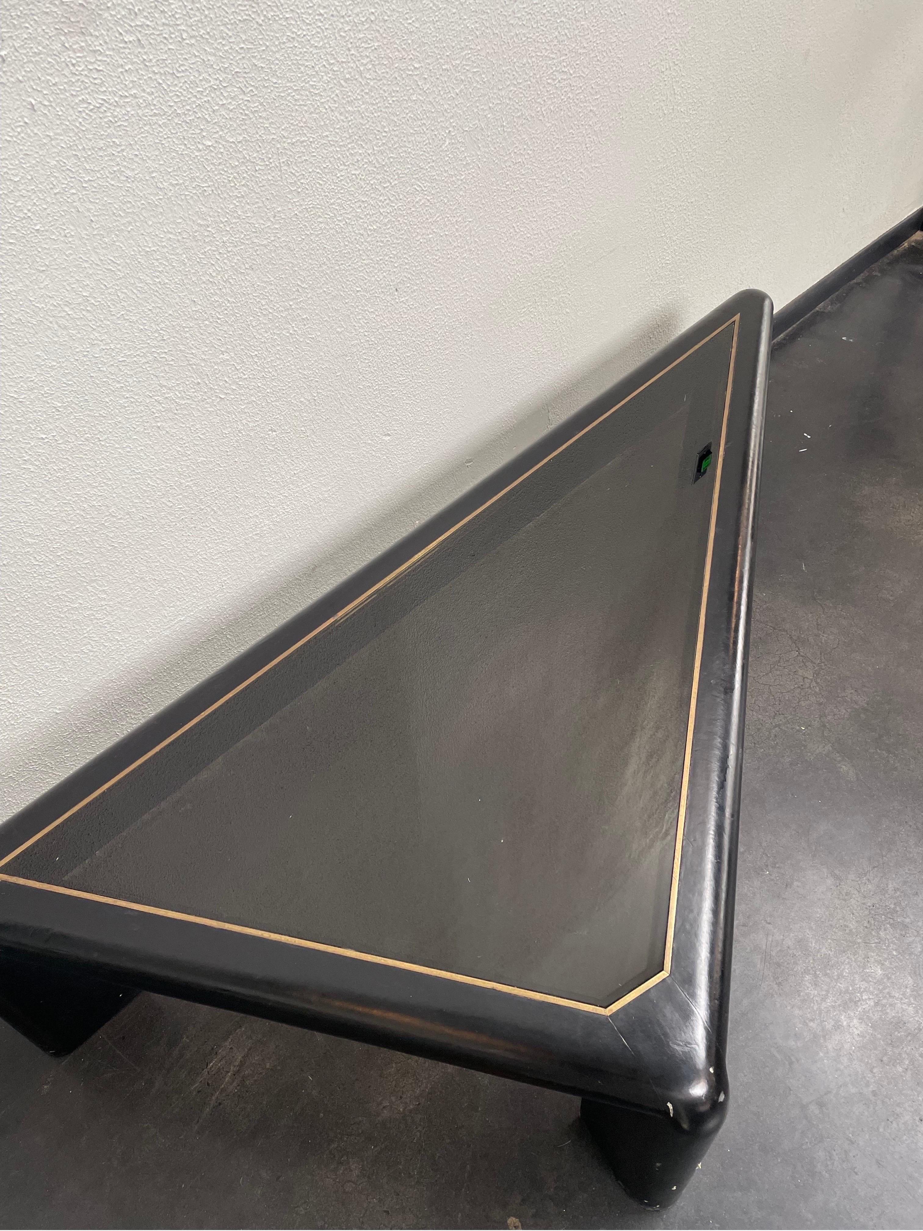 Vintage triangular coffee table encased in black leather and features a smoked glass inset.