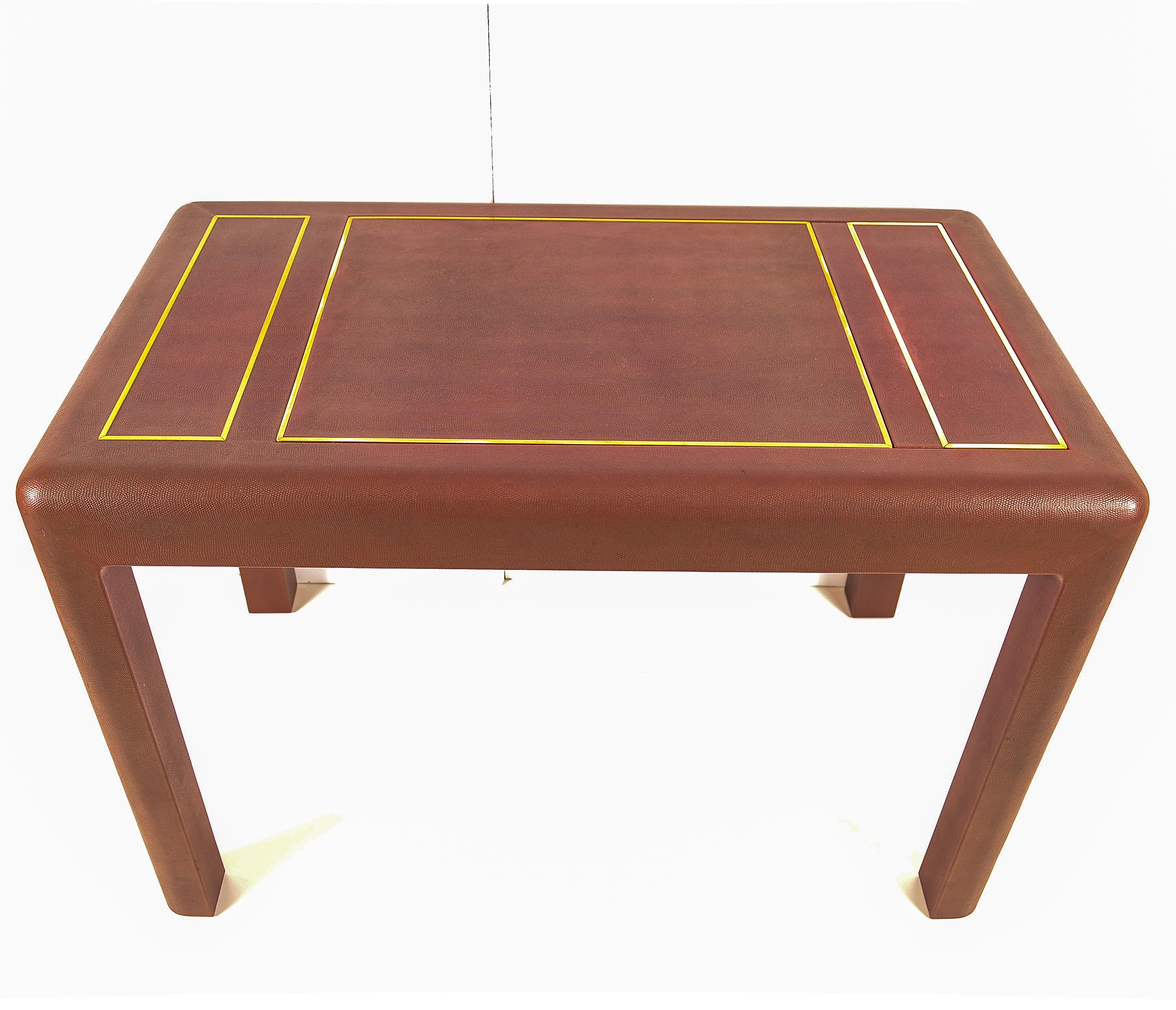 A most elegant game table covered in textured leather in an attractive cordovan color, with brass accents. Made with the unparalleled attention to detail and quality construction that made Karl Springer a design icon. The center panel pops up by