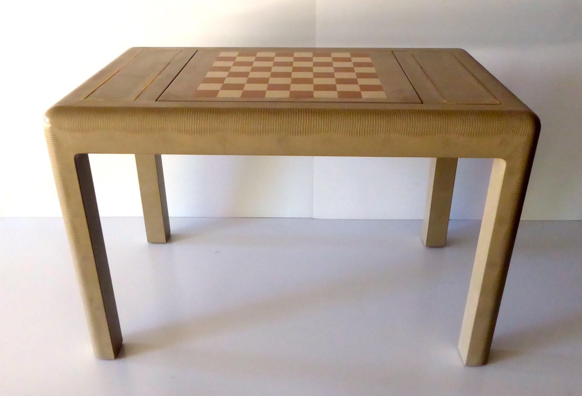 A vintage American lizard skin covered chess table, made by Karl Springer, circa 1986. The top of the table has three sections that are edged in brass. When the centre section is removed, it reveals a chess/checkerboard and one of the felt-lined