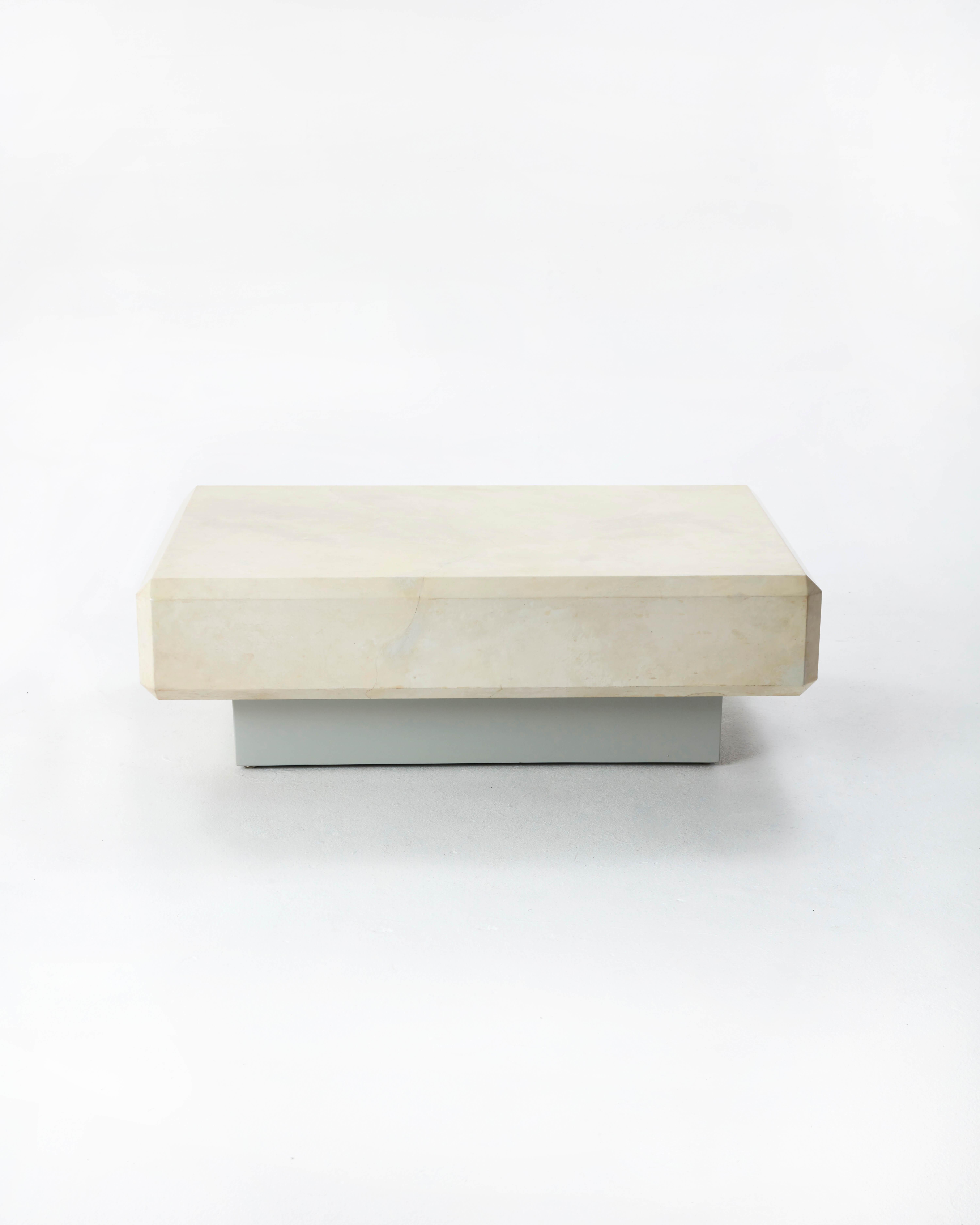 Cette table basse de Karl Springer se compose d'une base laquée avec incrustation et d'un plateau en parchemin de peau de chèvre, fini avec une laque transparente. Les bords biseautés et la base en forme de socle sont un clin d'œil au style Art