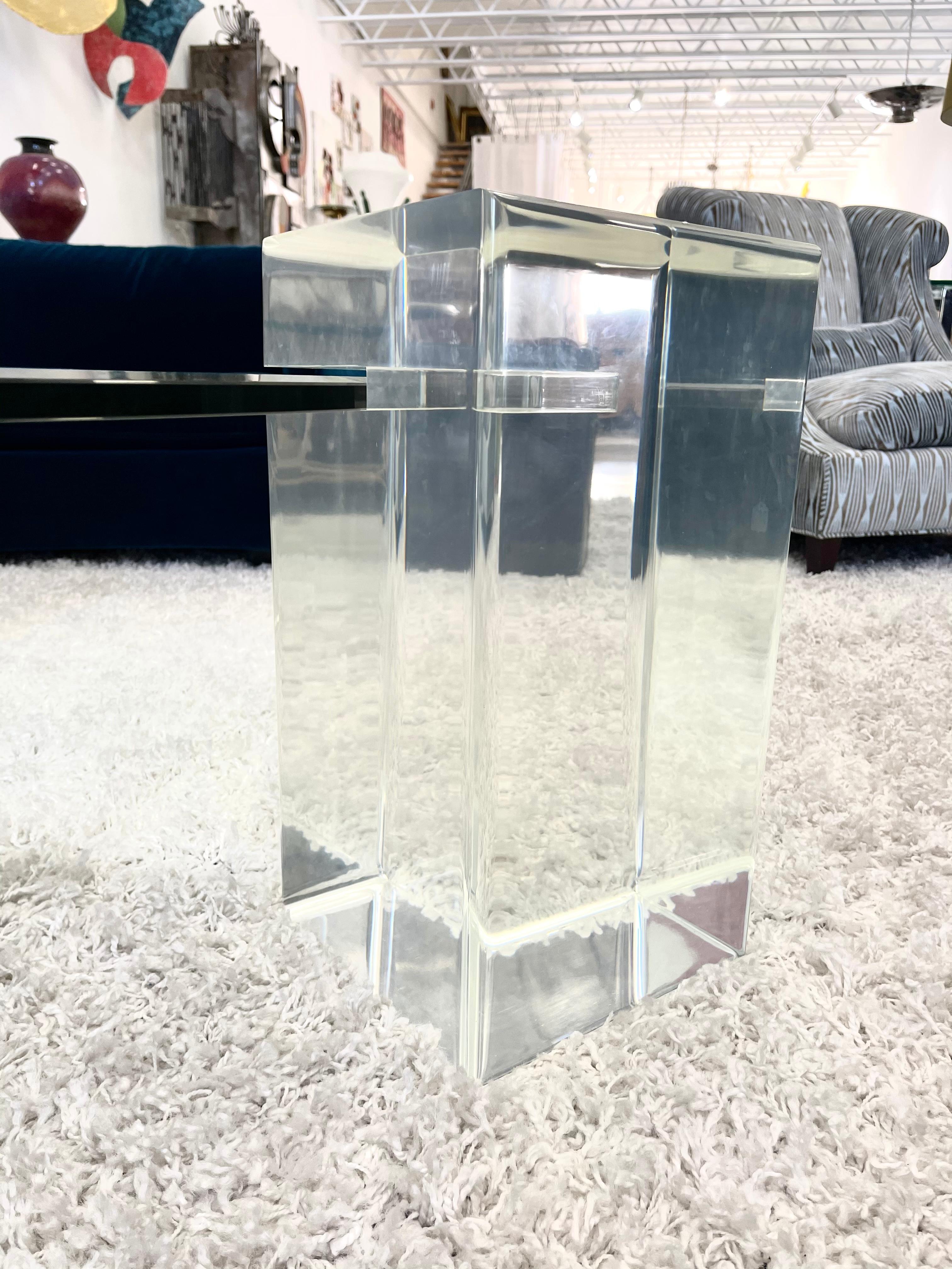 A vintage monumental Lucite coffee table in the style of Karl Springer.
Beautifully designed with the glass top floating from a singular Lucite cube and resting on 2 thick Lucite cubes of the same design
Larger Lucite block measures 19”.