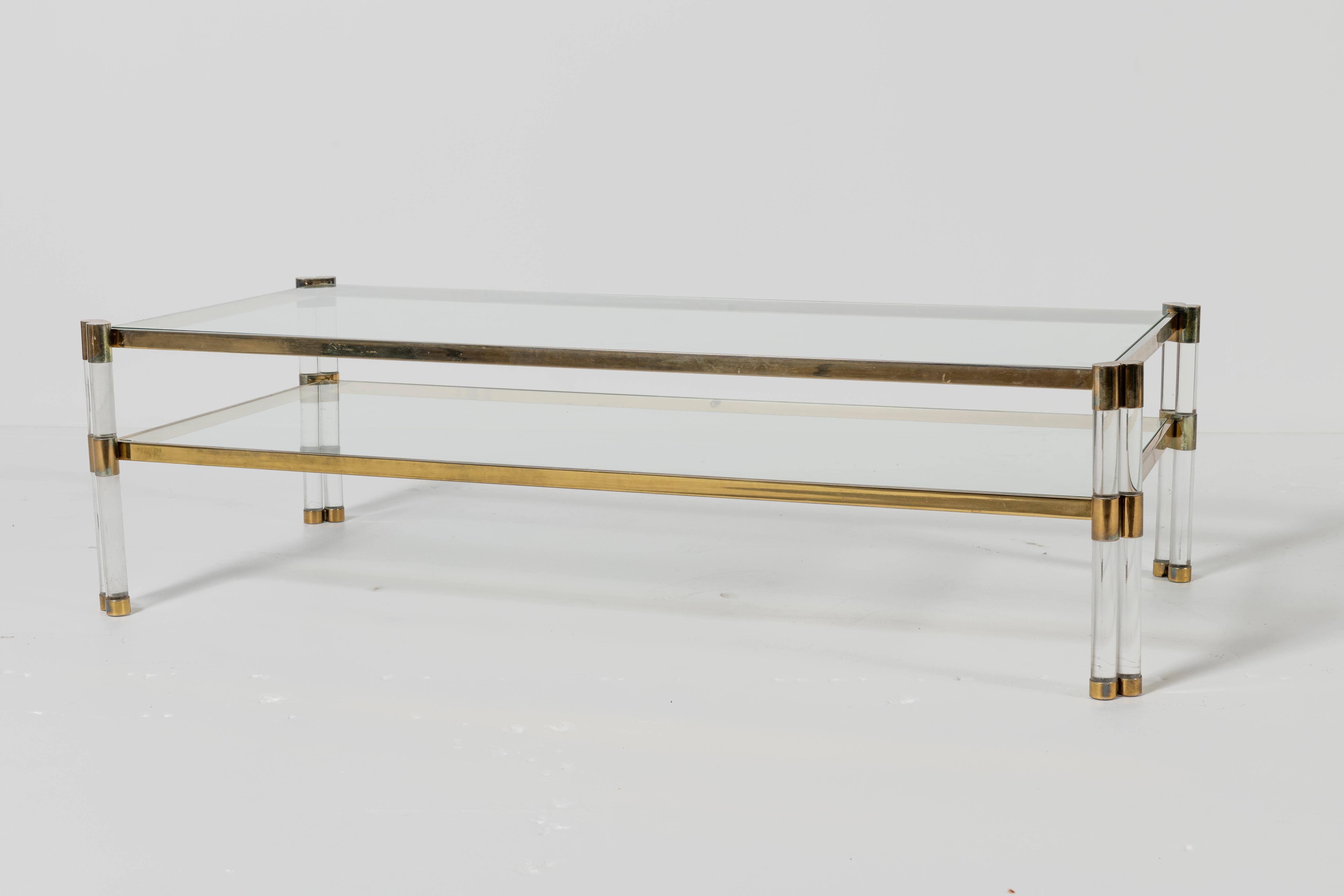 Vintage Karl Springer coffee table with shelf in lucite, glass, and brass. Shelf adds a layer for books or other objects, creating additional functionality.