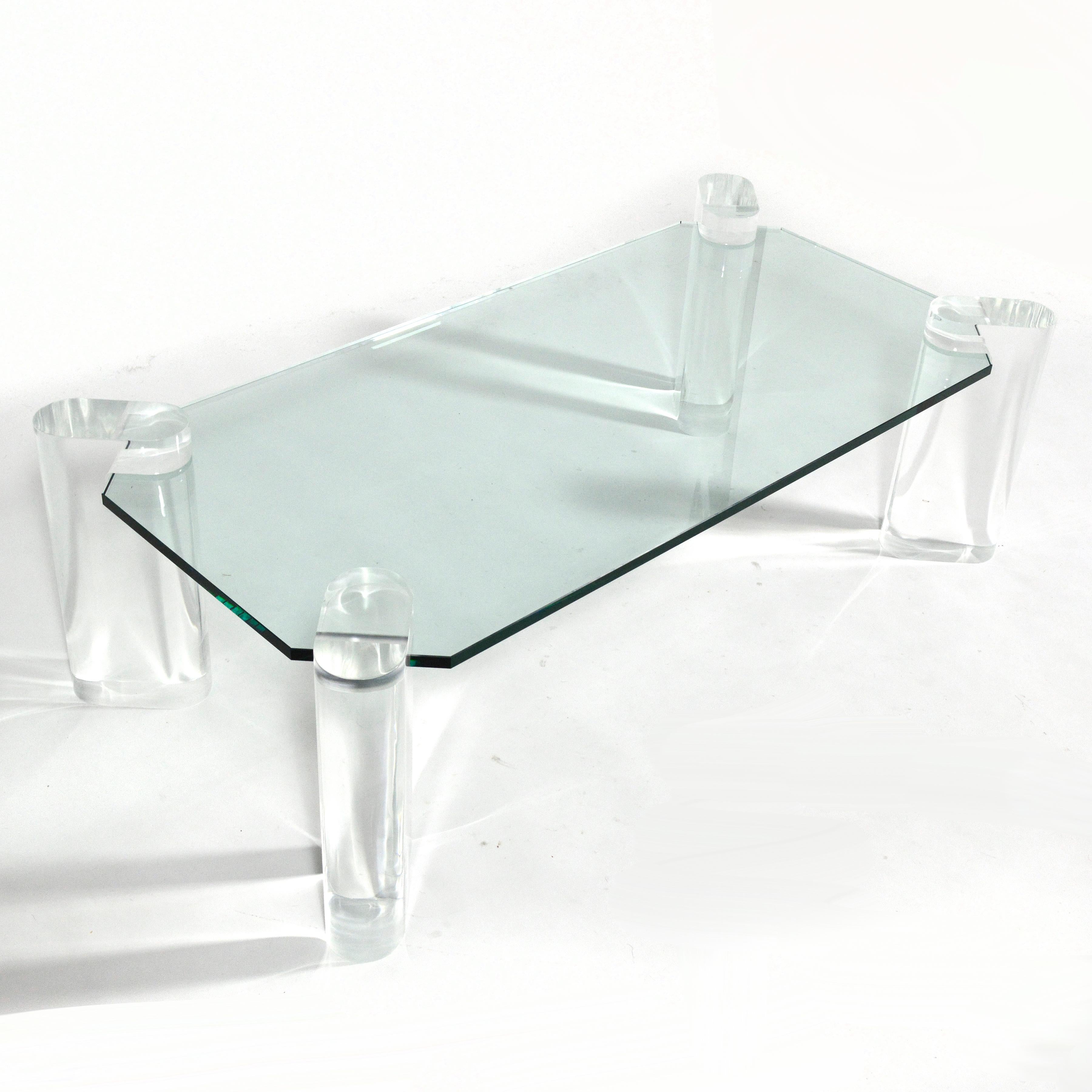 Stunning in it's simplicity and use of transparent materials, this coffee table by Karl Springer has four oval lucite legs with cut-aways that support the glass top which is notched in the corners. We think this design would also look terrific with