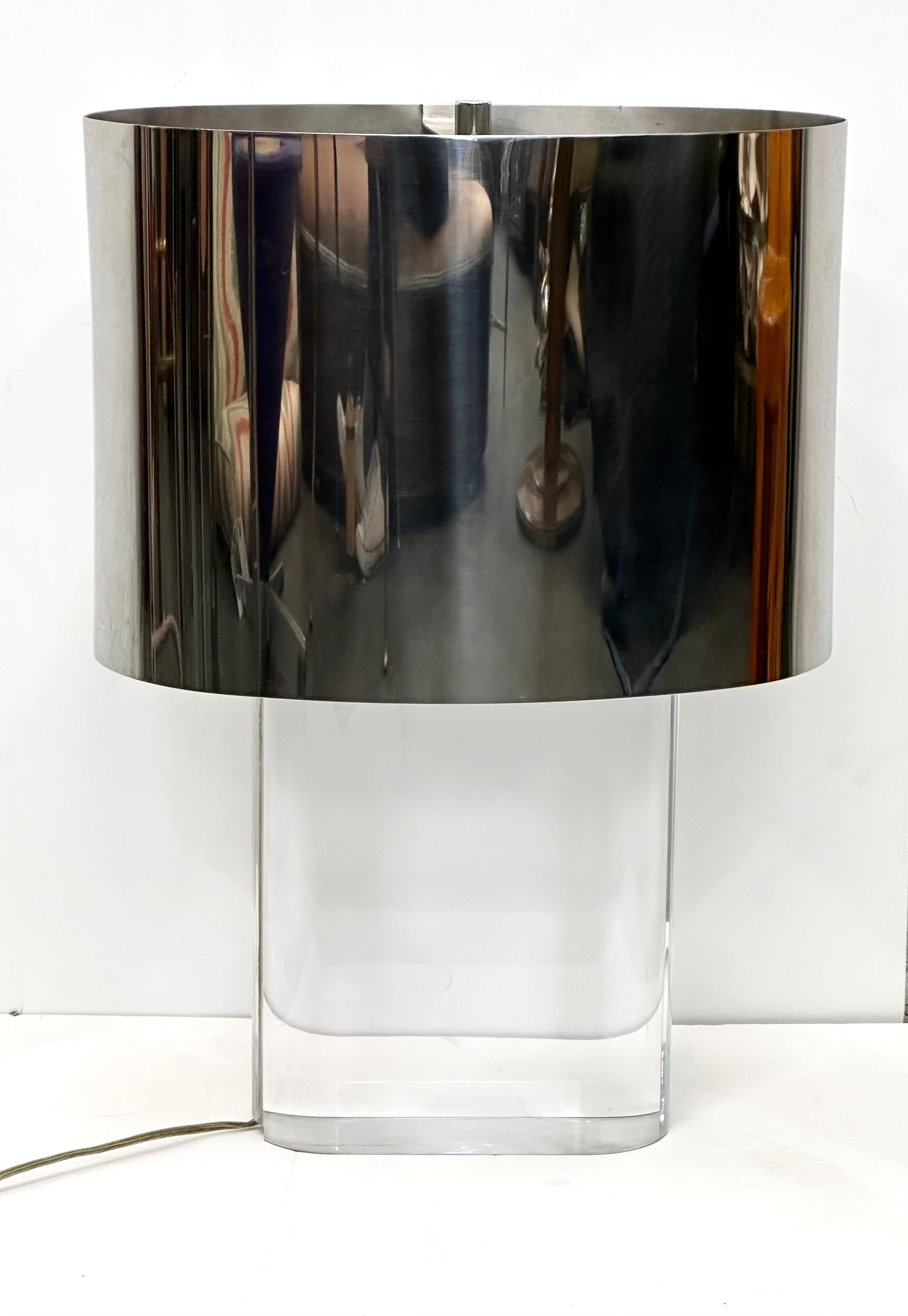 Rare solid clear acrylic oval block lamp with the original mirror-polished steel shade. Cord is embedded in the lucite block, which supports a double cluster socket and adjustable riser to change shade height. 

This classic and revered Springer