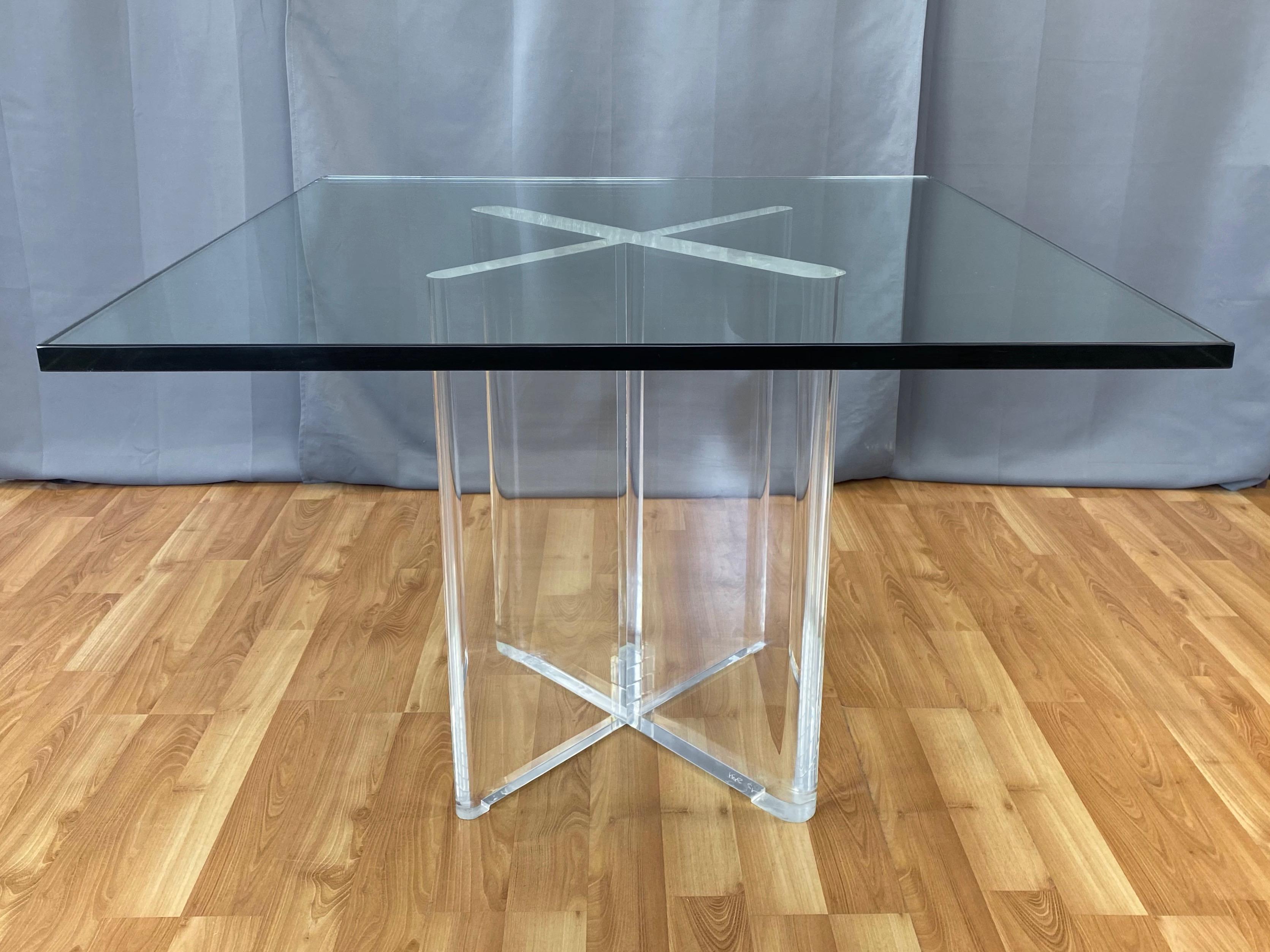 A very impressive and rare 1970s lucite X-base dining table by Karl Springer with extra-thick square glass top.

Strikingly sculptural and substantial solid lucite base comprised of two intersecting rounded-edge slabs, with one being