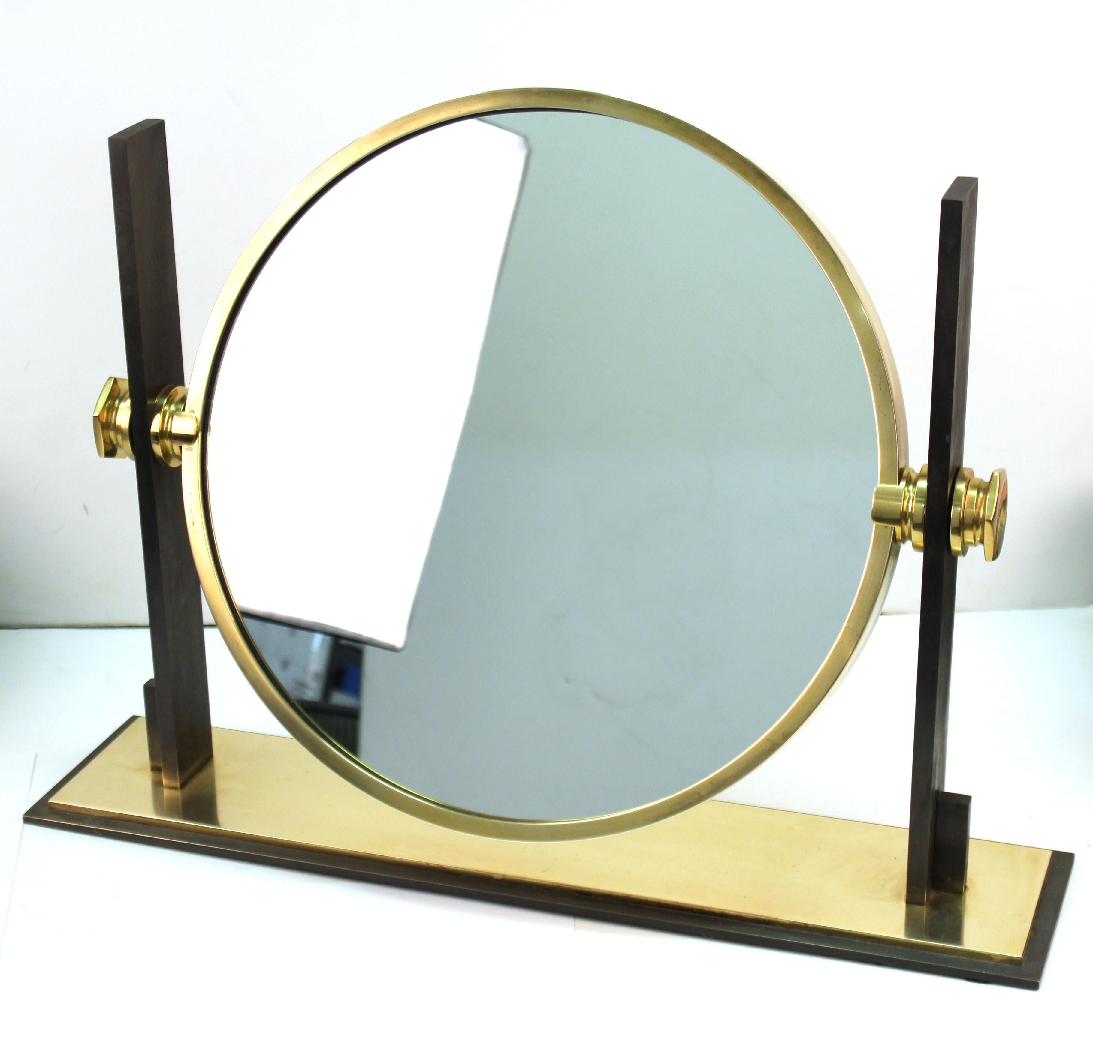 Modern round vanity or table mirror designed by Karl Springer. The piece is made with a brass and heavy steel structure. Mirror revolves and can flip from the convex side to a flat regular side. In great vintage condition with age-appropriate wear.
