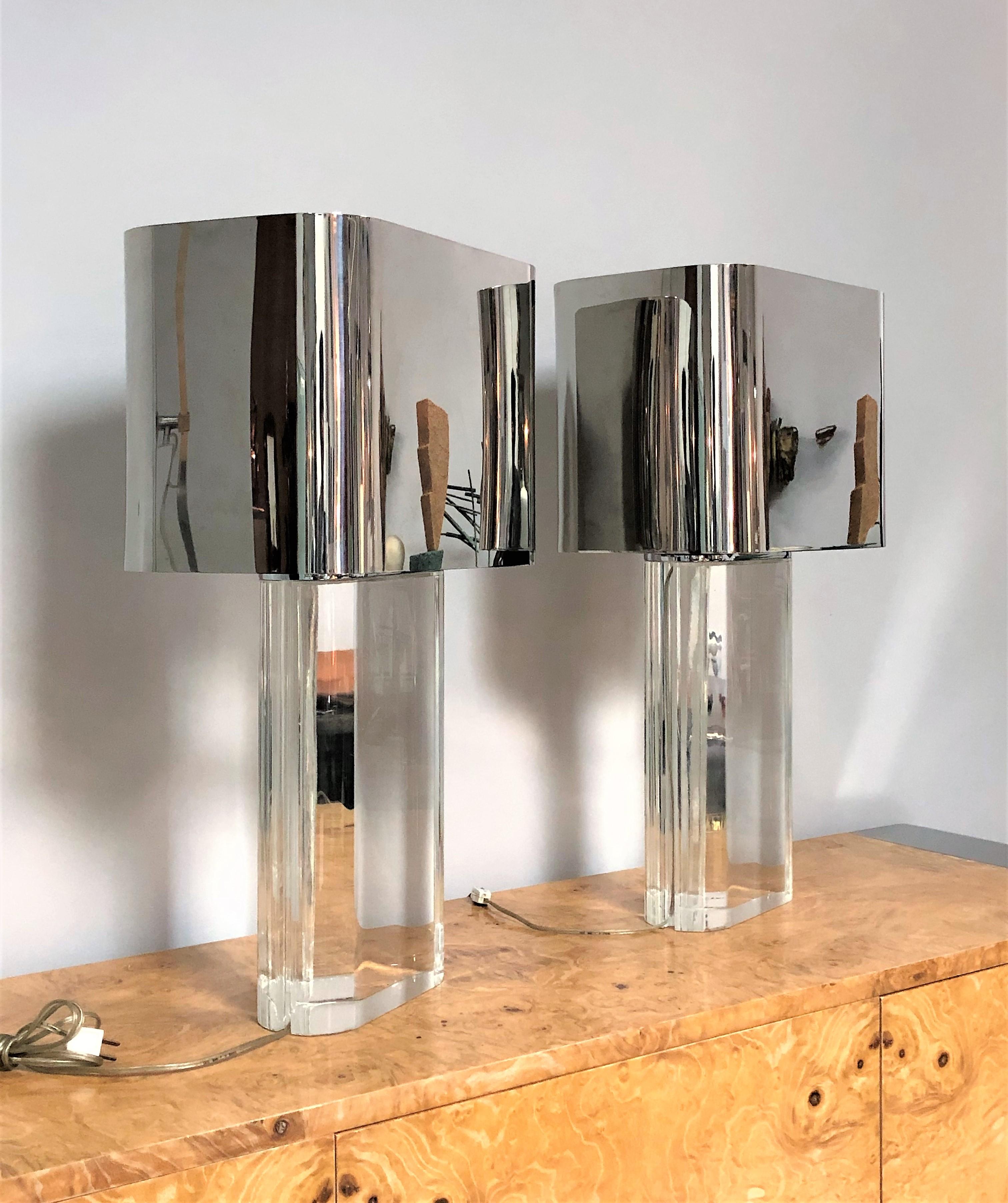 A pair of Iconic Lucite lamps with heavy stainless steel shades. The bases are solid, the original mirror polished stainless steel shades are heavy and perfectly proportioned. Lamps retain original finials and the always missing diffusers on the