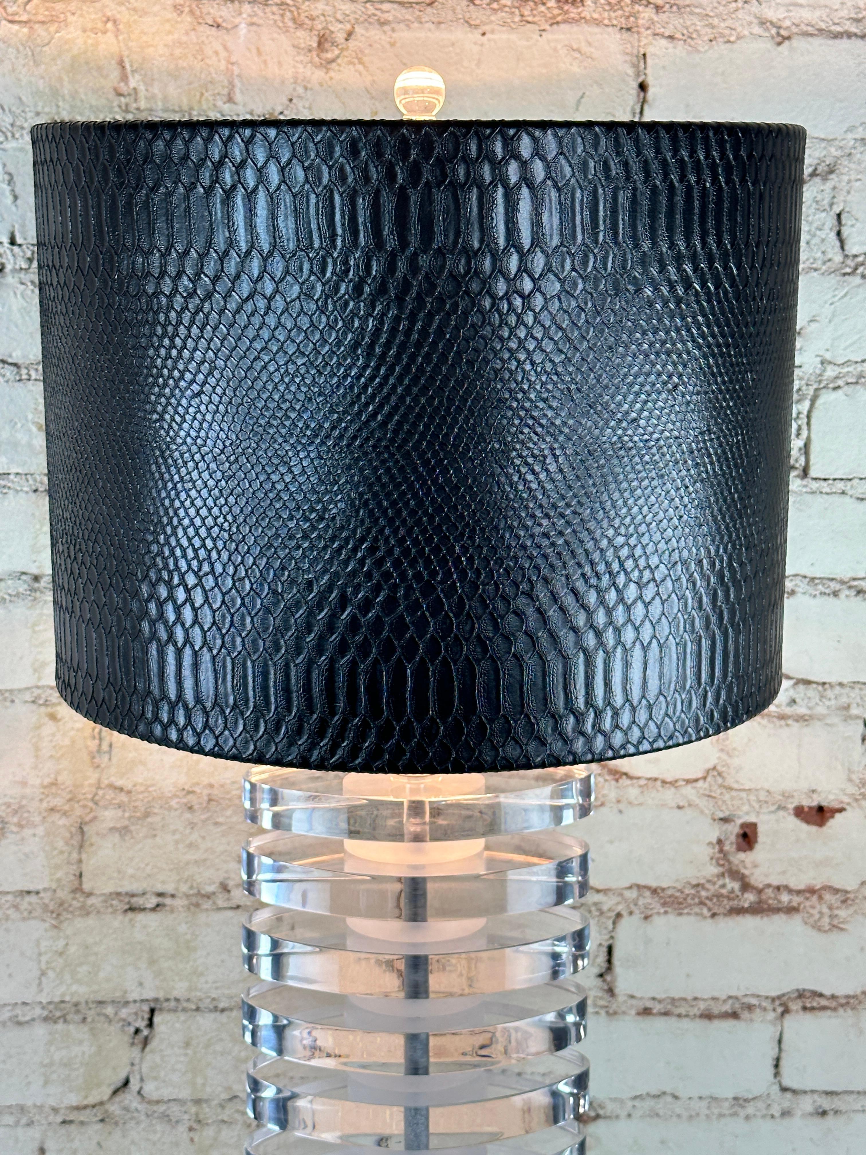 This table lamp is made with stacked Lucite disks. assembled on the chromed steel stem.
The shade is made in faux lizard with a silvered paper interior.
It was designed by Karl Springer,in the 70s.