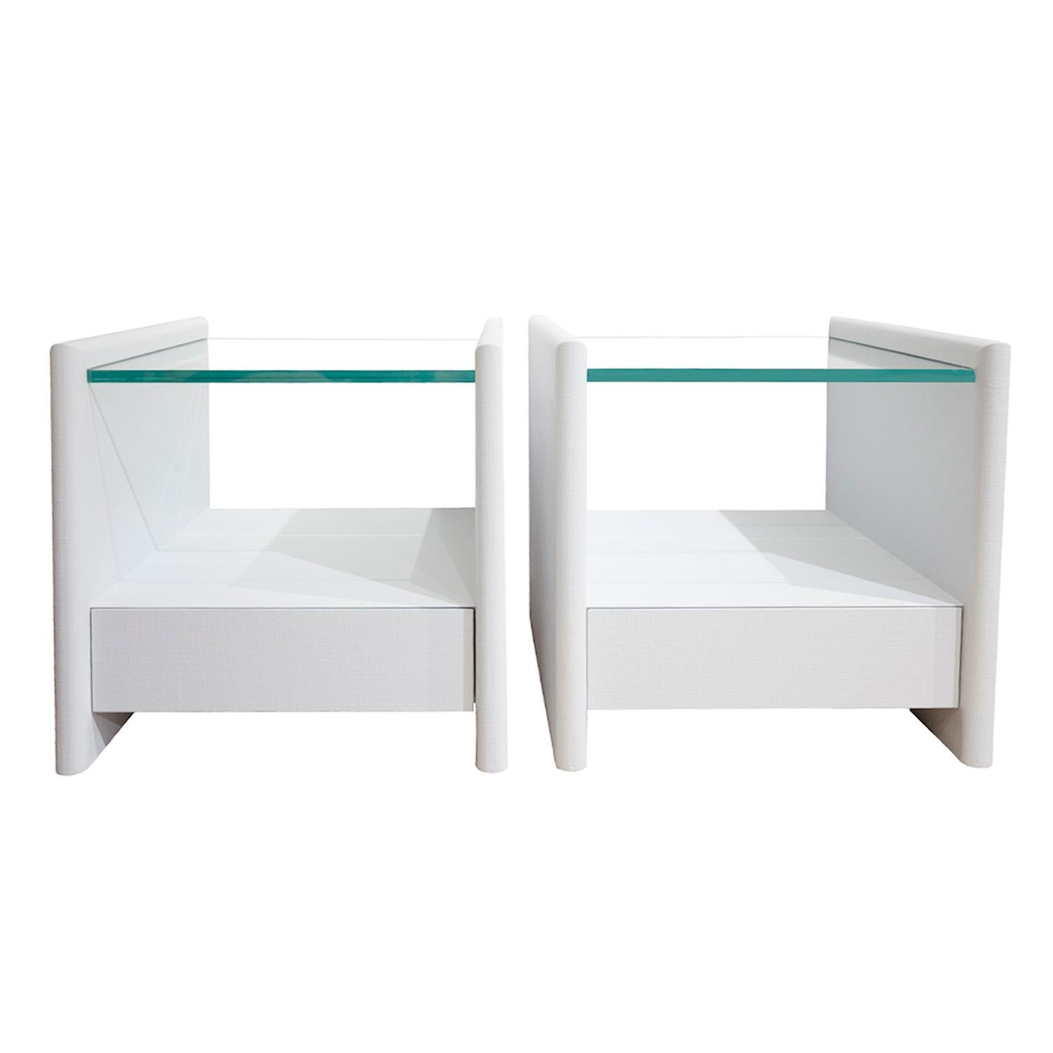 Pair beautifully made elegant bedside tables in gray lacquered linen with thick glass tops by Karl Springer, American 1980's. These have been newly relacquered by Lobel Modern.  A timeless design.
