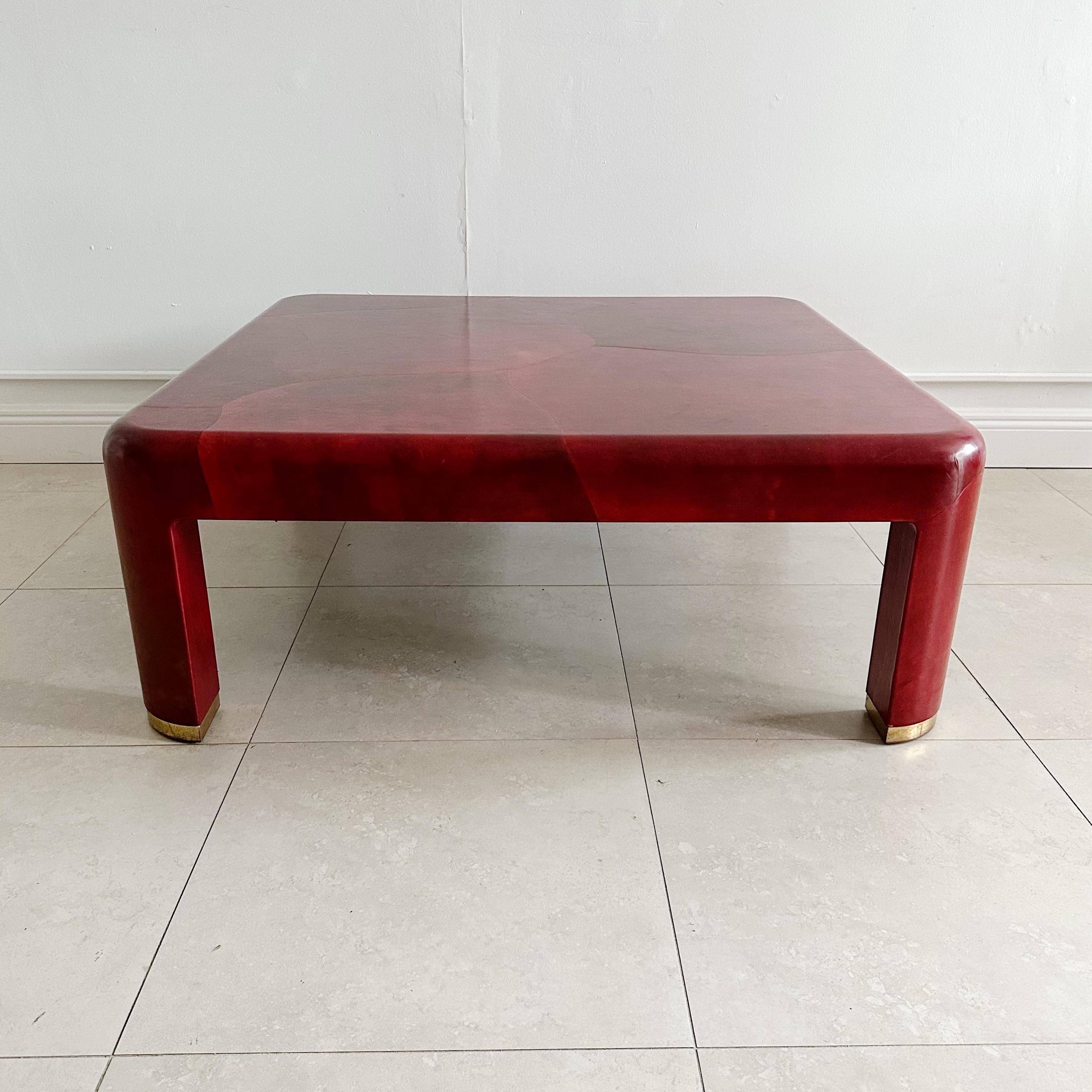 Square red leather clad coffee table with brass feet by Karl Springer from the 1980s. This piece has been professionally restored. Brass feet can be polished but left with slight patina to show age. Shows minor age appropriate wear to surface and is