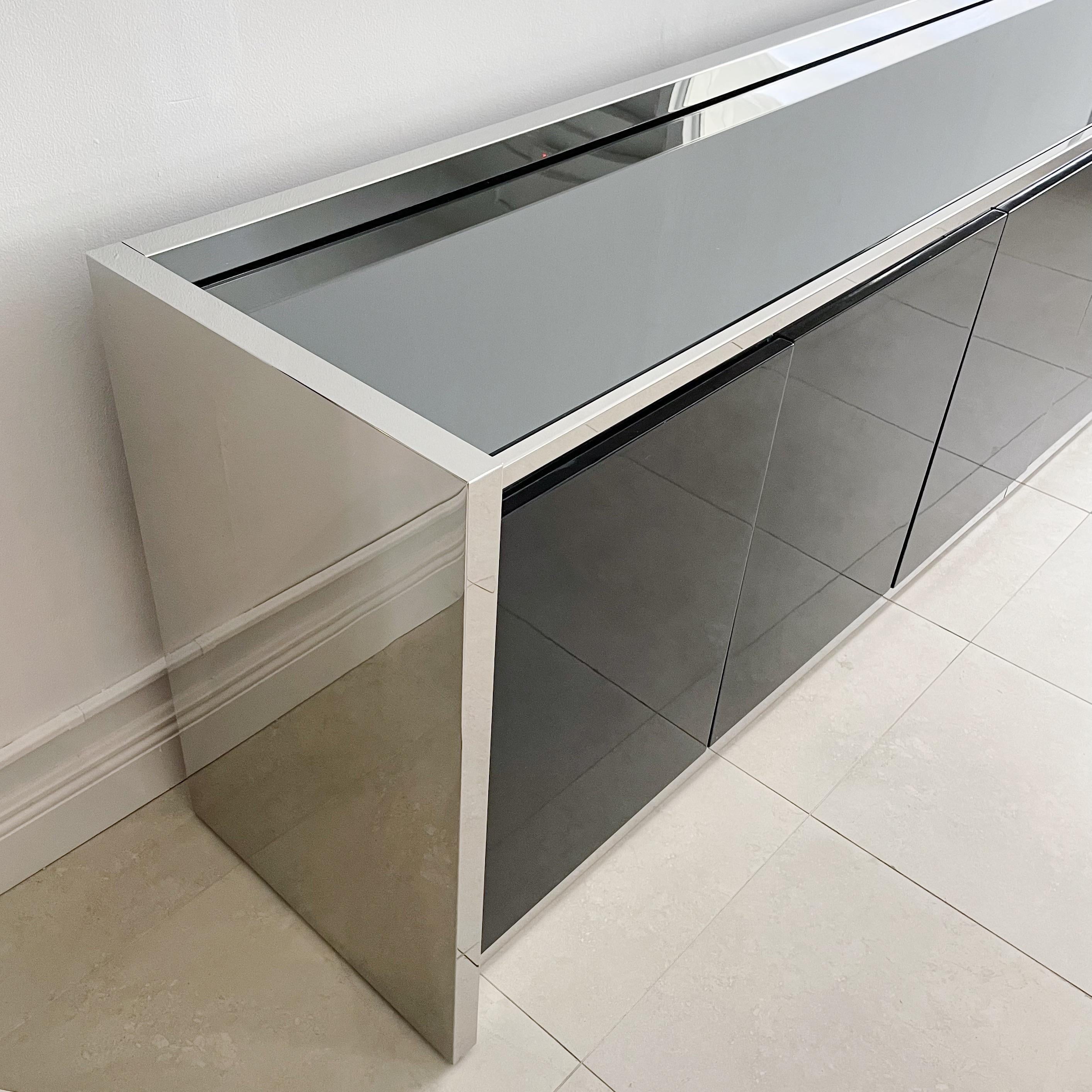 Custom Karl Springer six door, polished stainless steel and black lacquer credenza. The interior has adjustable shelving, a wine rack that can easily be removed and two drawers on the far right section. This cabinet can be seen published in the