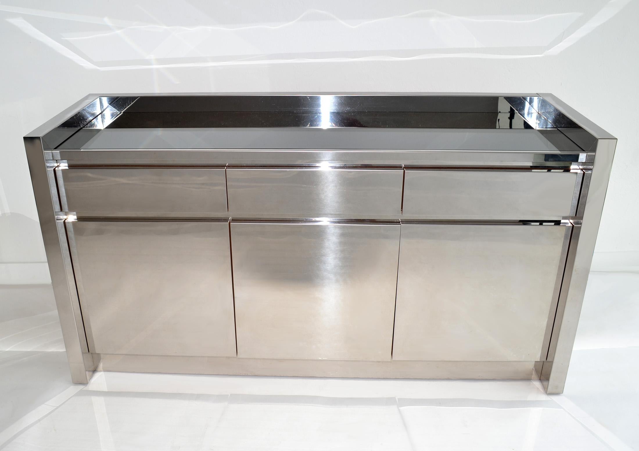 Buffet o credenza con cassetti in acciaio inossidabile Karl Springer, USA, anni '80
Server, buffet, credenza, cassettiera o armadietto in acciaio inox lucido e legno con tre cassetti e tre ante che racchiudono ripiani interni e un piano in vetro