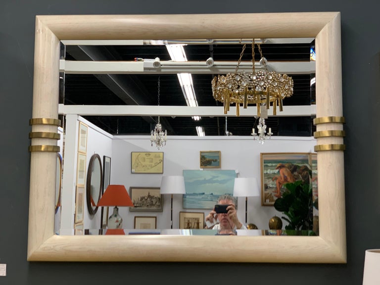 Elegant large Art Deco mirror in the style of Karl Springer. The composition is pickled oak and brass framing a mirror. This is a large wall mirror measuring: 55 inches wide by 45 inches tall and in great condition. Works well in many different