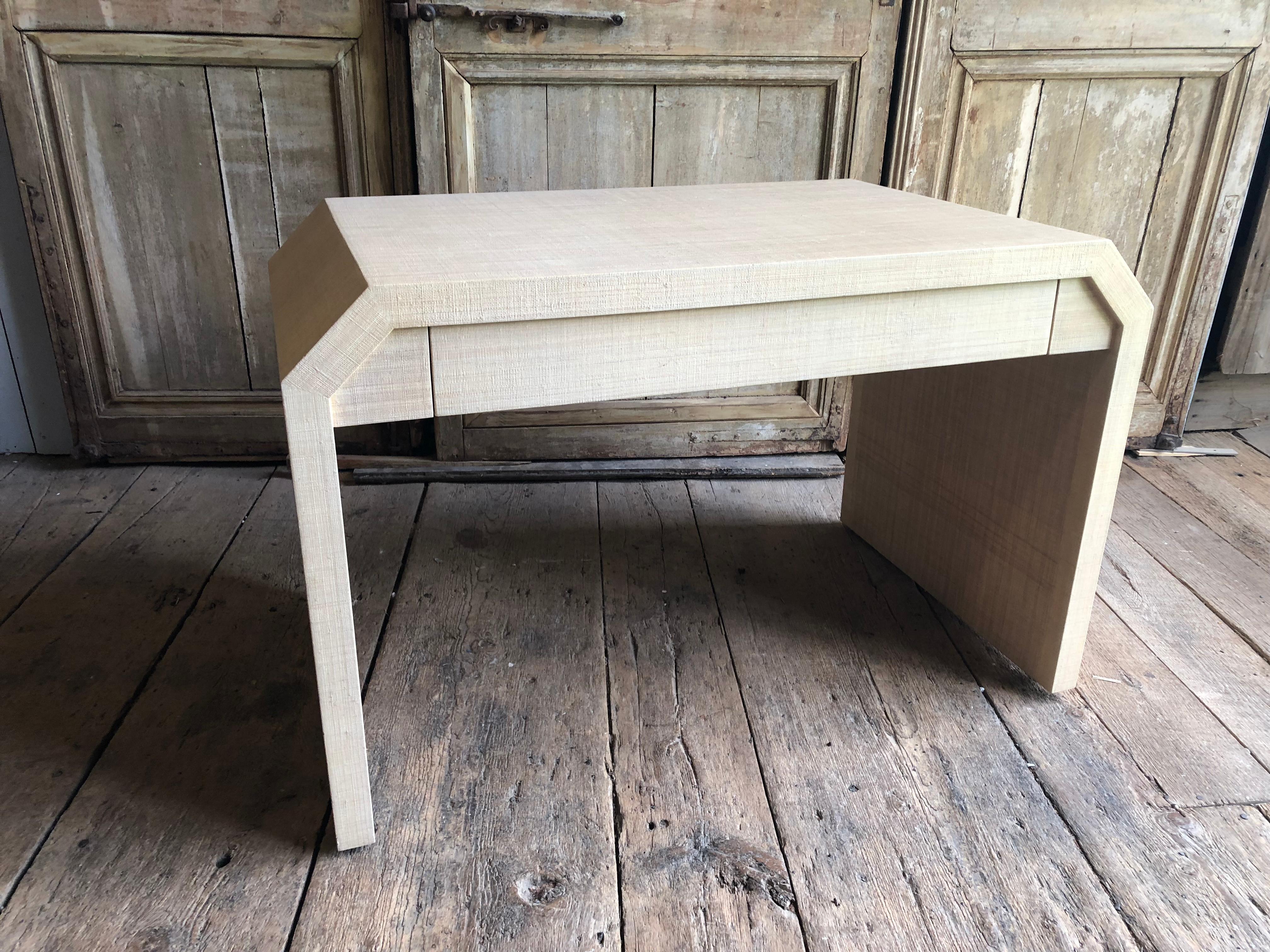 A lacquered grass-cloth covered modern desk or vanity table in the style of Karl Springer, with a long drawer in the apron, circa 1970.