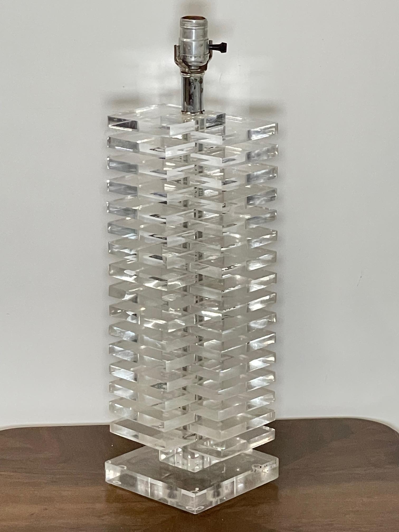1970s lucite table lamp features modern, hollywood regency styling with individual stacked squares of lucite and a lucite base. Stands 22