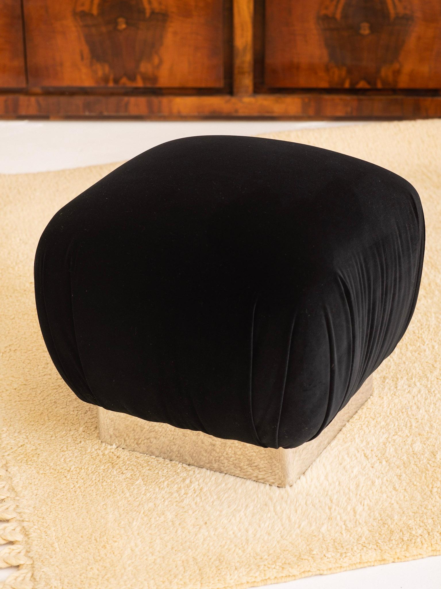 Classic Hollywood Regency soufflé ottoman in the style of Karl Springer. Pleated black velvet upholstery and chrome plinth base.