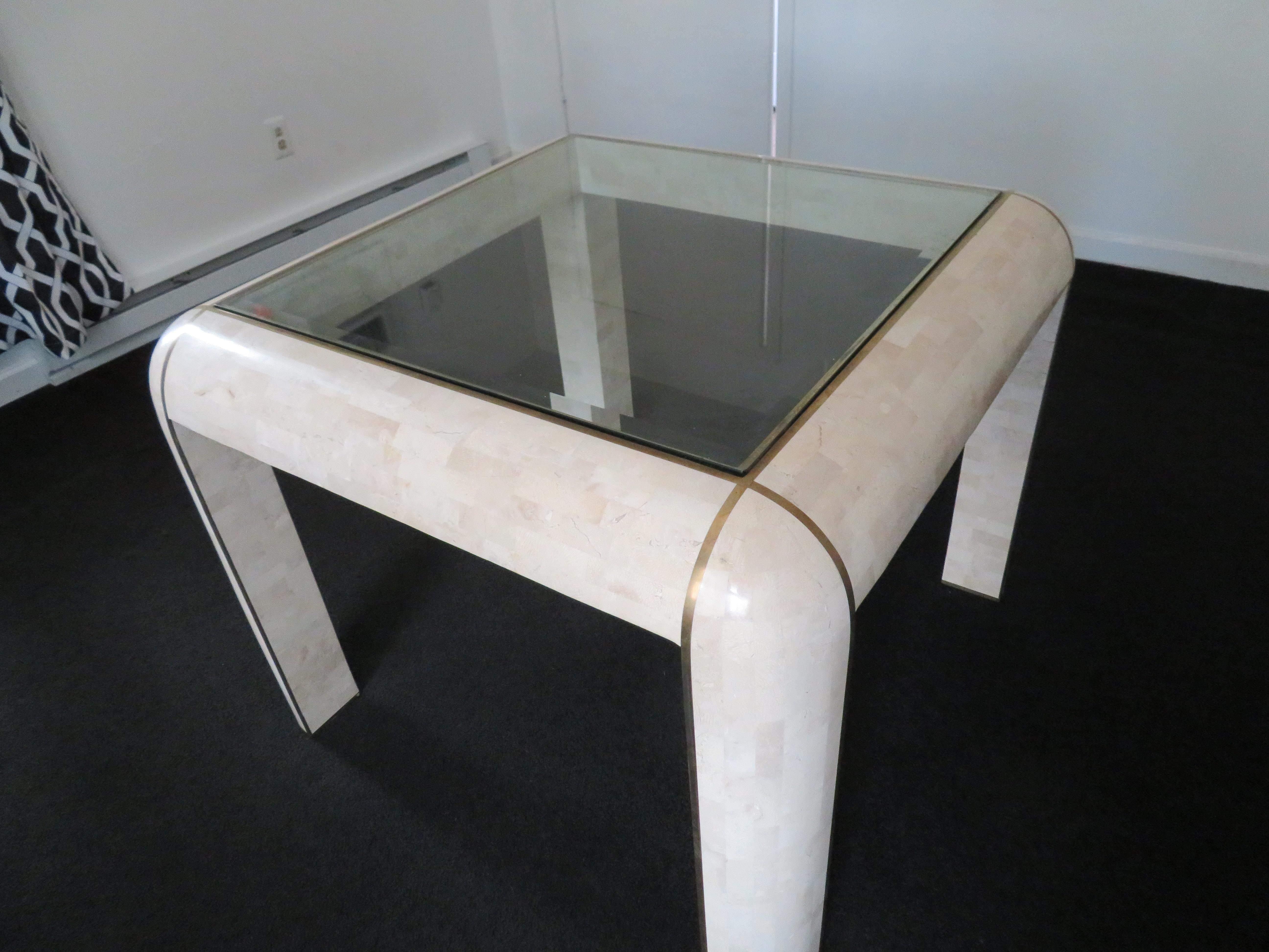 Mid-Century Modern game table in the style of Karl Springer, 1970s. Tessellated stone with brass banding and glass inset top. 38
