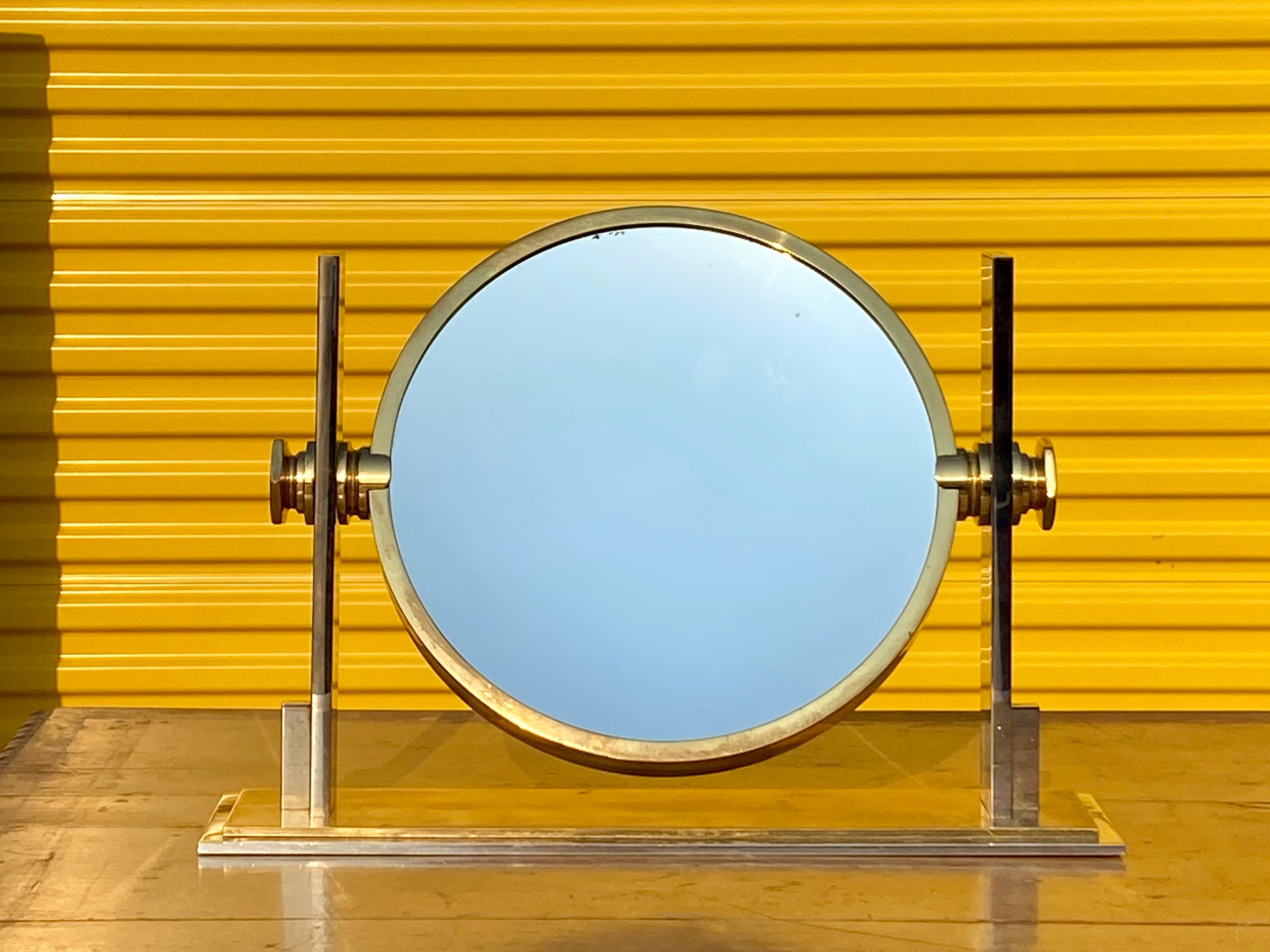 A brass and steel vanity mirror by Karl Springer.
The mirror rotates and has a standard and a magnifying mirror.
   