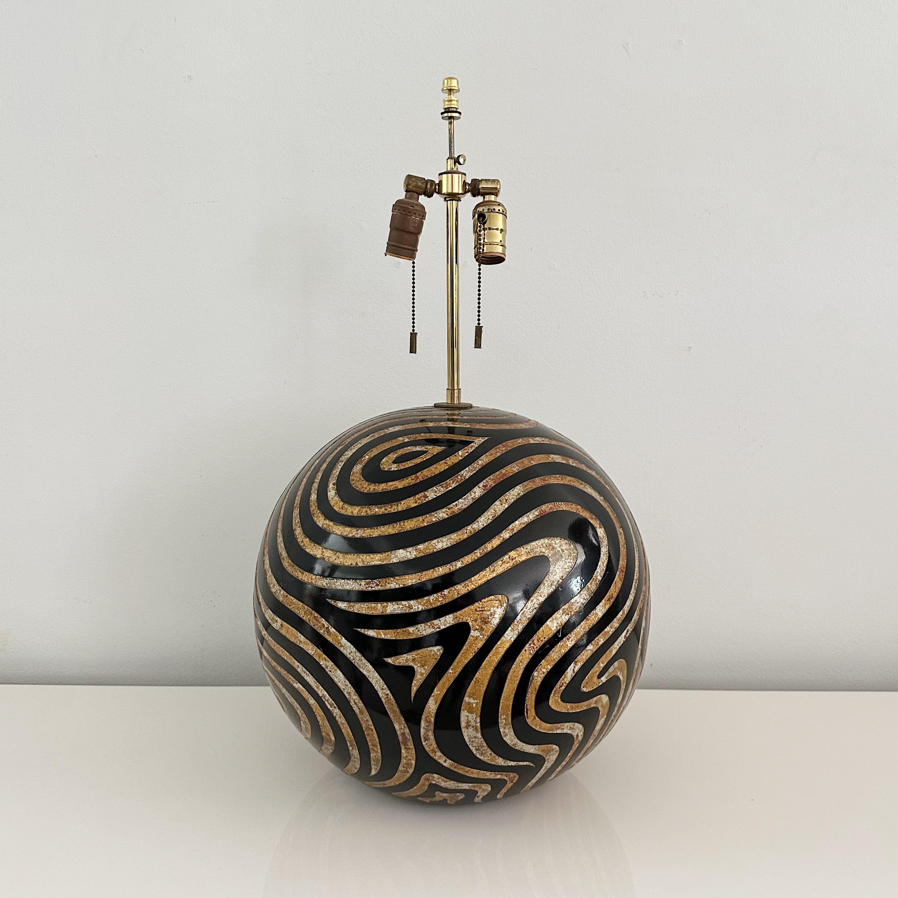 Vintage Karl Springer 1979 Gold & Silver Leaf Incised Black Wood Ball Table Lamp

This table lamp, designed by the renowned Karl Springer in 1979, is crafted with attention to detail and artistic finesse.

The lamp's central element is a beautifully