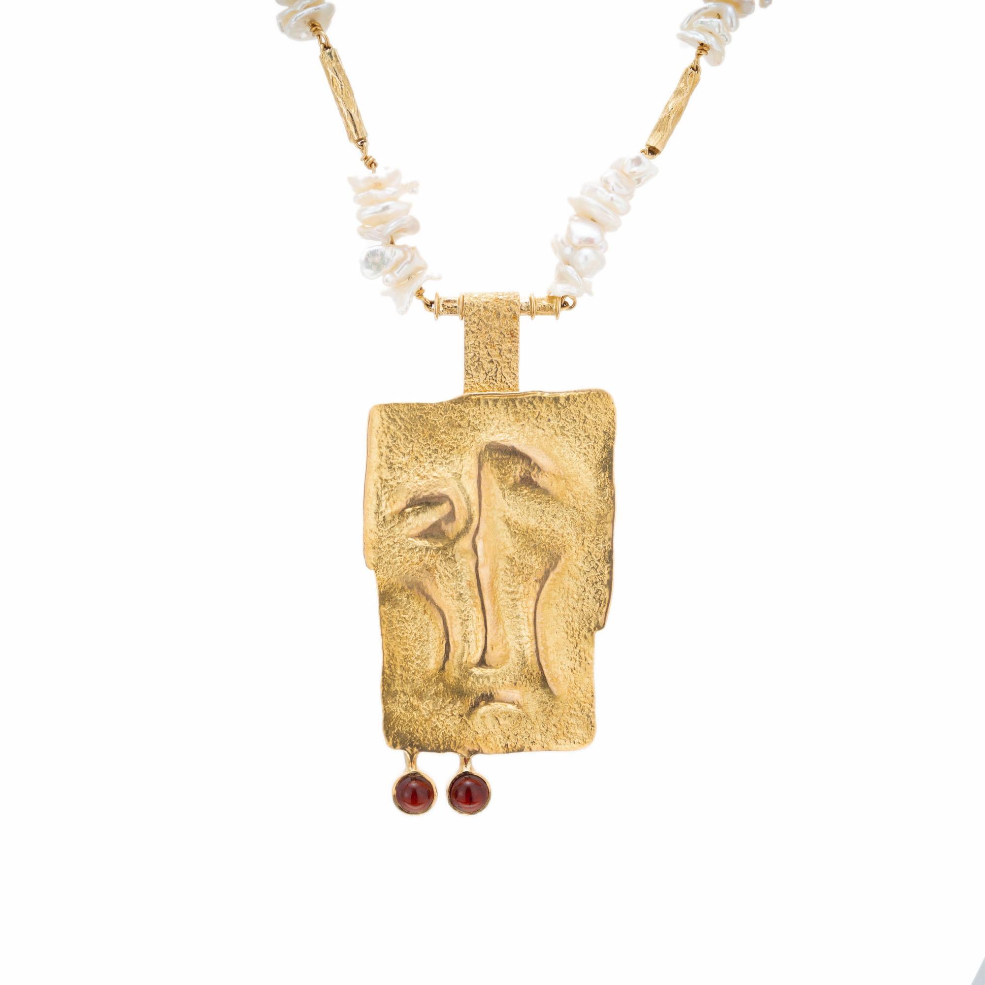 Karl Stittgen freshwater pearl and garnet pendant necklace. Two-piece necklace allows the center pendant to be removed and each worn separately. Toggle clasp with a 22 inch chain.

120 freshwater pearls 
2 round red cabochon garnets, 5mm
18k yellow