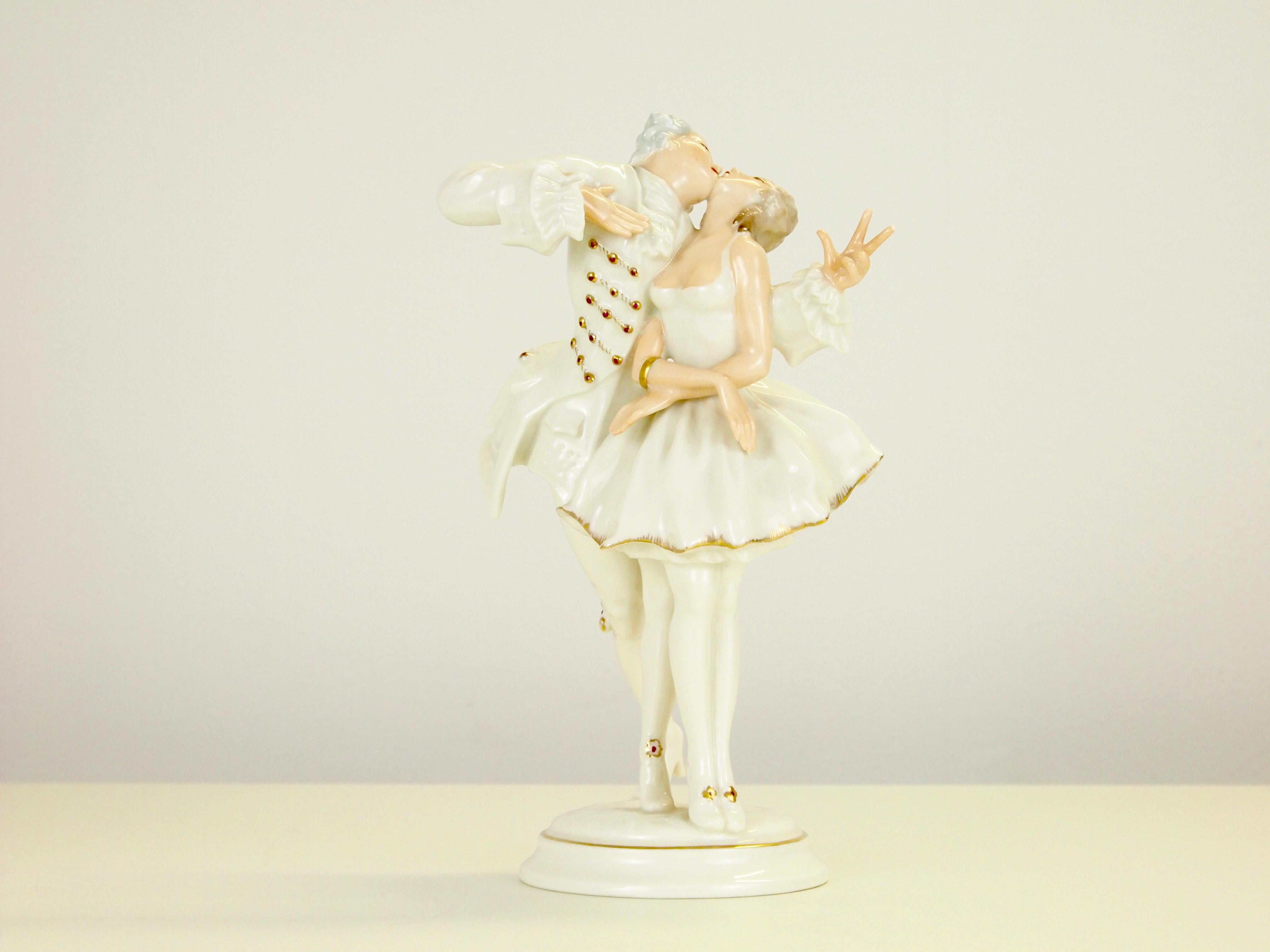 Vintage midcentury fine porcelain figurine depicting a romantic dancing couple in romantic dressing just starting to kiss.

The figurine is mostly white glazed with golden accents and has hand painted body parts. It dates from the period 1955-1969