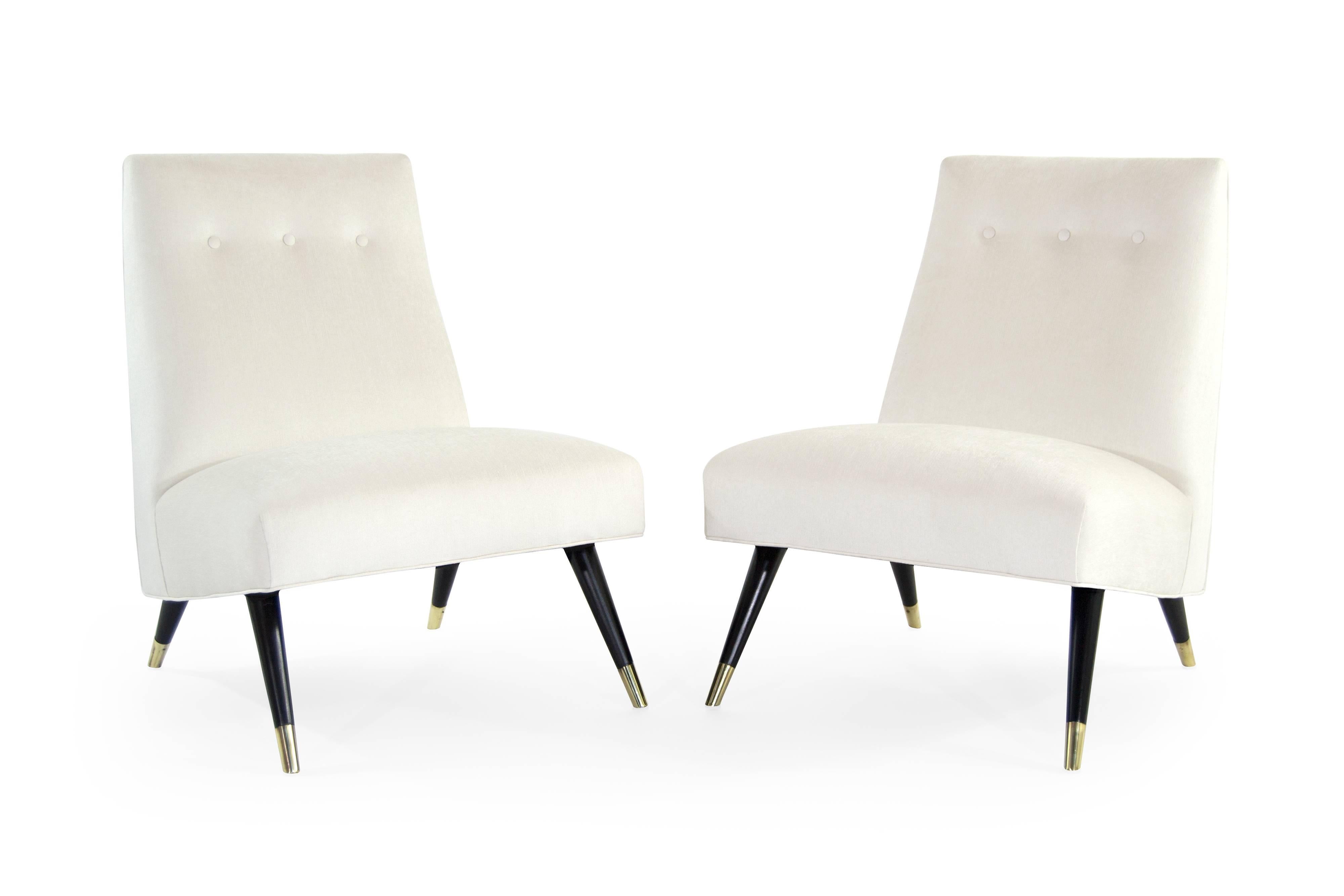 Pair of low profile lounge chairs by Karpen of California, circa 1950s. Newly upholstered in ivory cotton linen by Kravet. Legs fully restored to its original ebonized finish. Brass sabots newly polished.