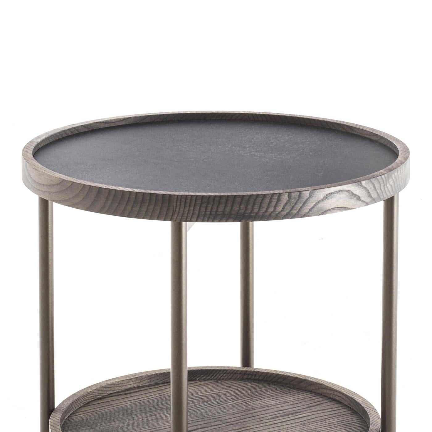 Table d'appoint Kart avec structure métallique en finition bronzage. 
Avec plateau inférieur en frêne massif et plateau supérieur en roche. 
Les extrémités des pieds sont en laiton bronzé brossé.