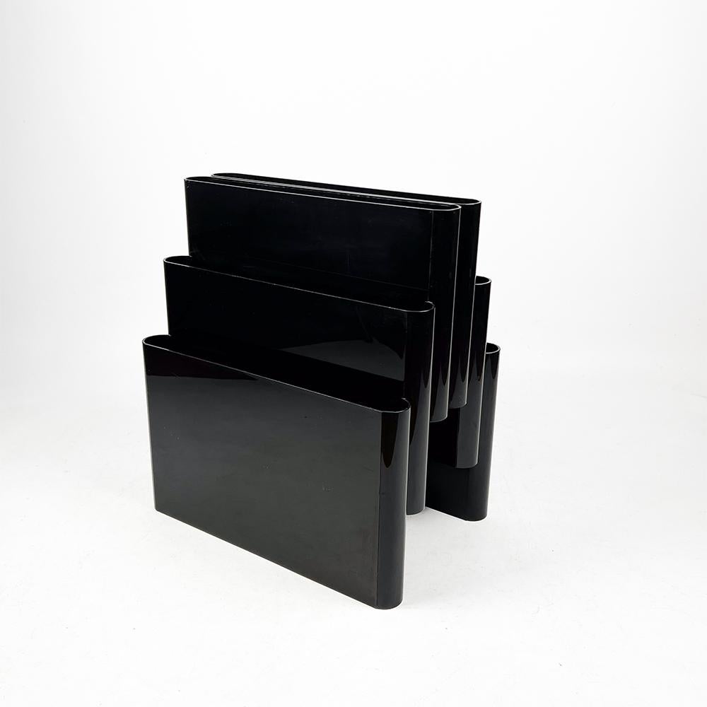 Kartell 4675 magazine rack designed by Giotto Stoppino in 1971.

Made of black PMMA plastic.

6 compartments.

It has scratches from use on the lower sides, visible in the photographs.

Measurements: 45x30x40 cm.