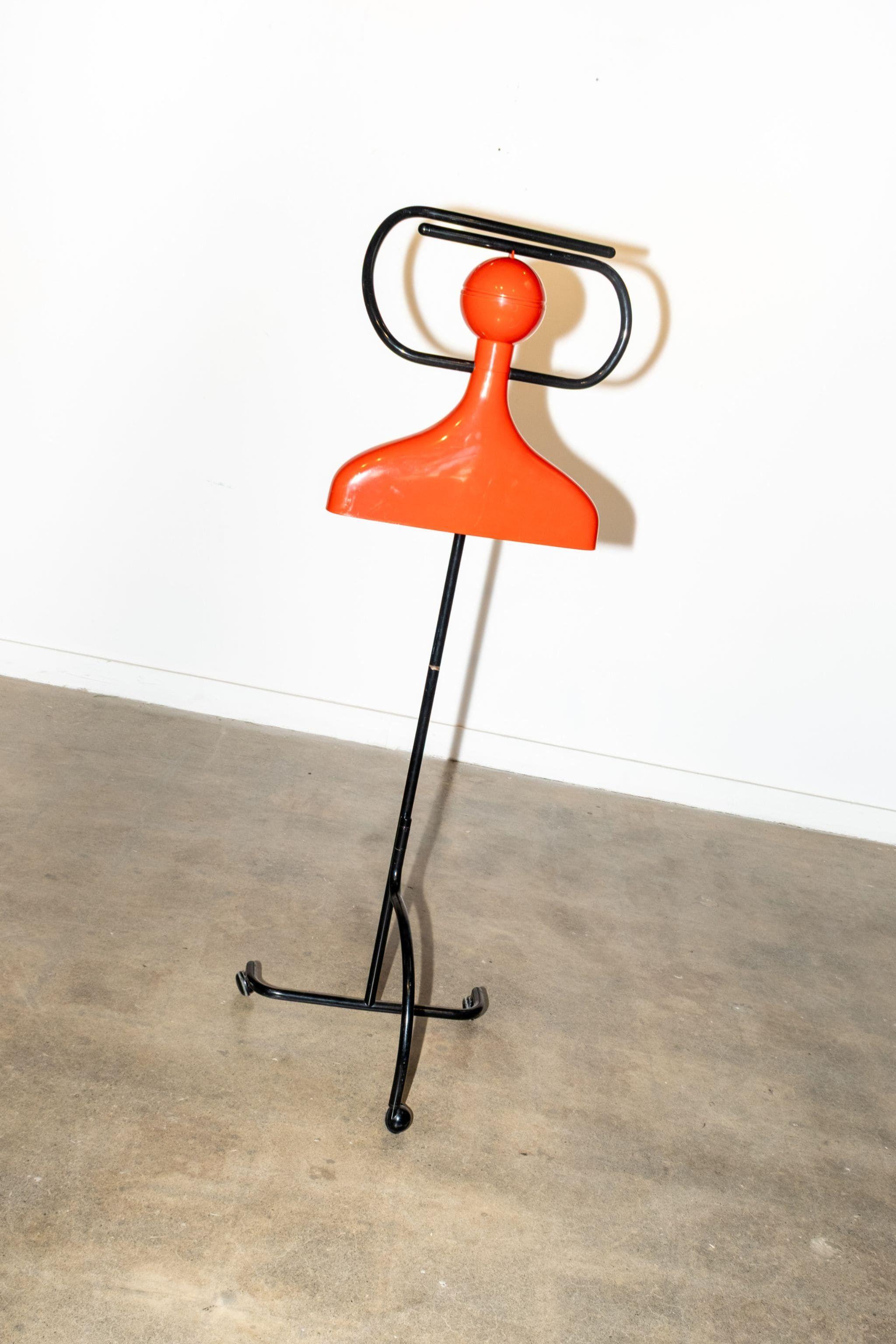 Aparcacoches de pie de metal tubular negro y plástico rojo, diseñado por Anna Castelli Ferrieri en 1989 y producido por Kartell en la década de 1990. Dos brazos móviles y una bola de plástico en la 