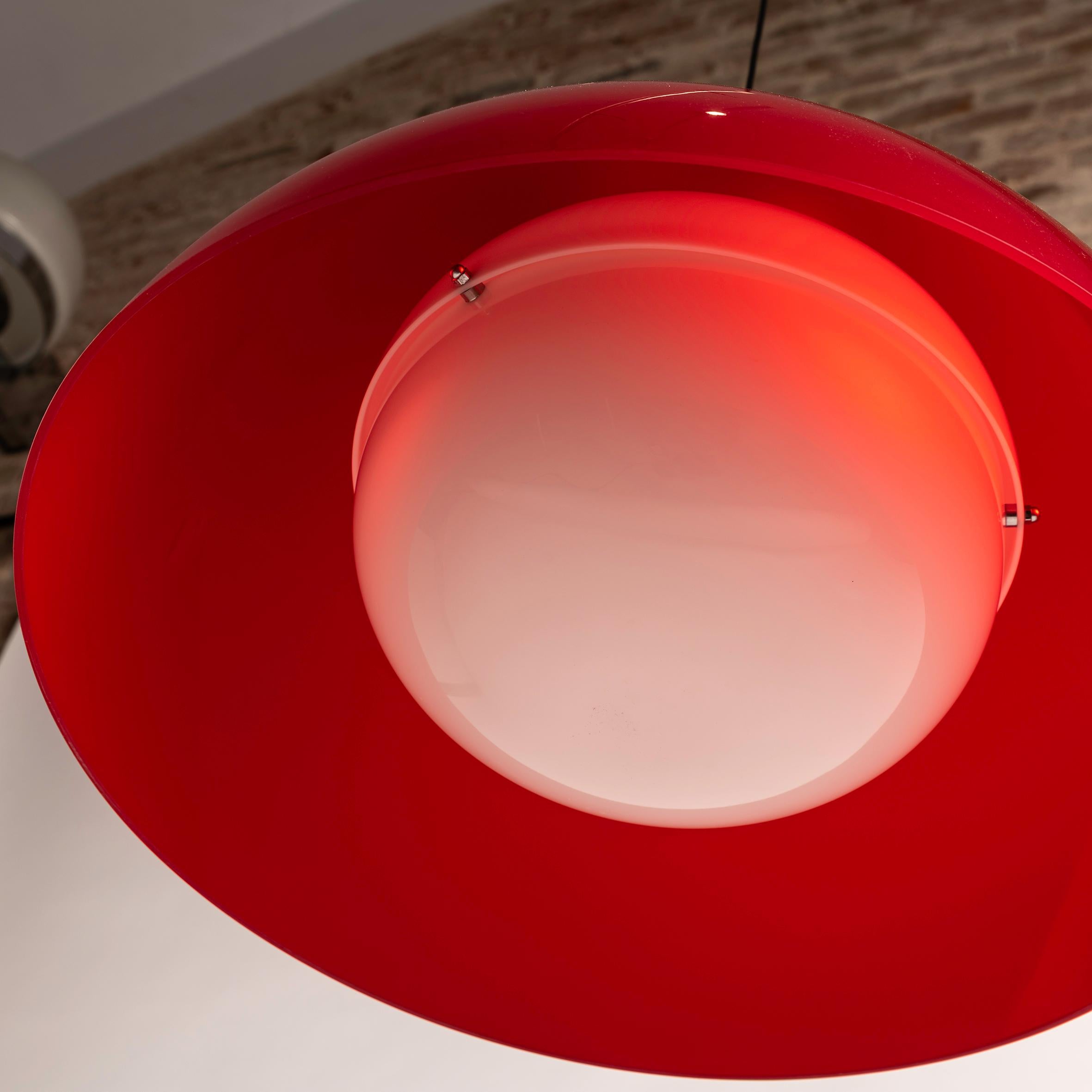 Die rote Kartell/Tramo KD6 Pendelleuchte, entworfen von den legendären Achille und Piergiacomo Castiglioni, ist der Inbegriff von zeitloser Eleganz und innovativem Design. Diese in Collaboration mit Tramo hergestellte Pendelleuchte ist ein