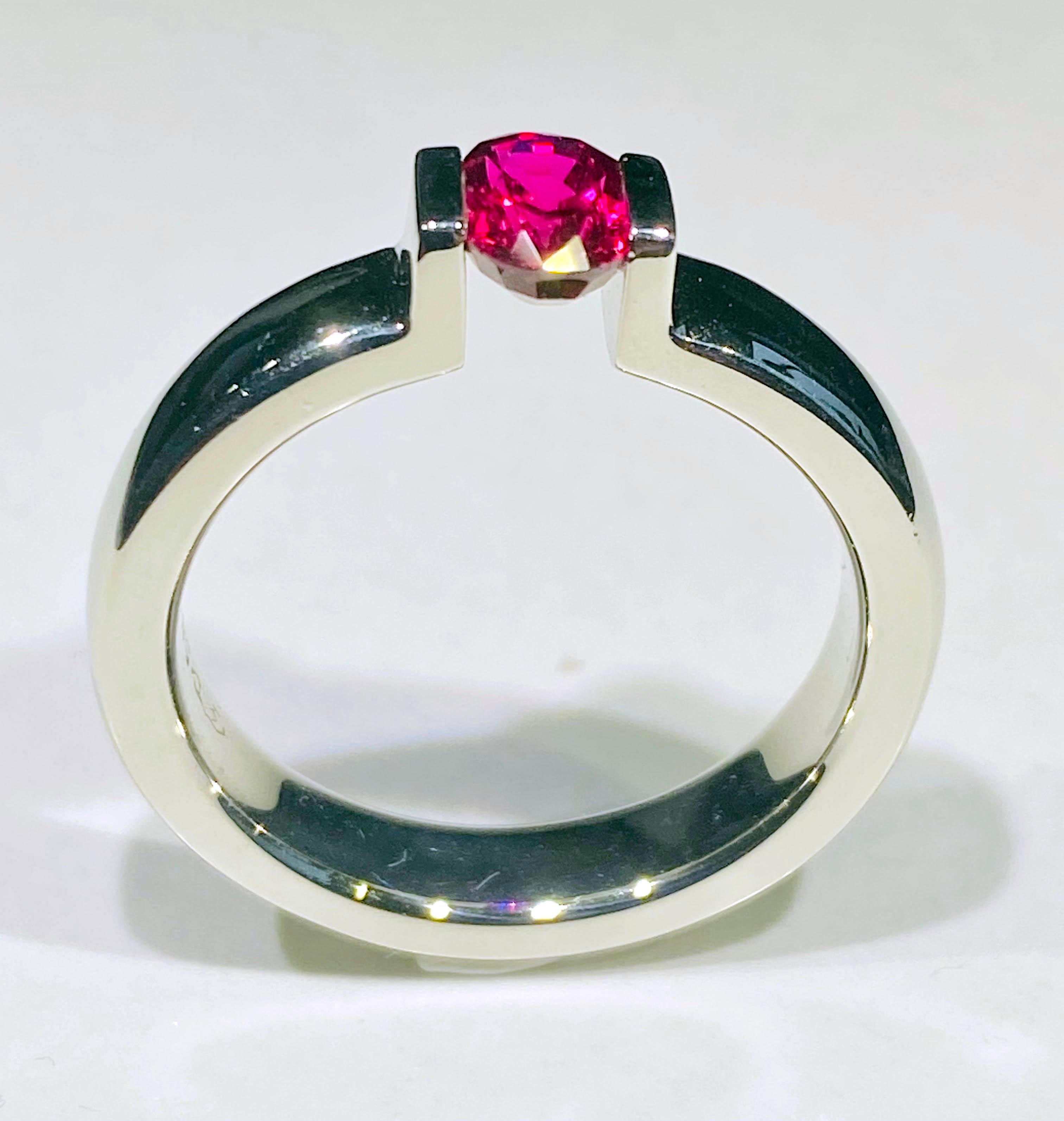 This 1 Carat Ruby is set in a 14kt White Gold tension band. The Ruby is held tightly in place by tension from the White Gold band. The Girdle of the Ruby is nestled in small grooves on either side of the band. The Ruby is very secure and shows all