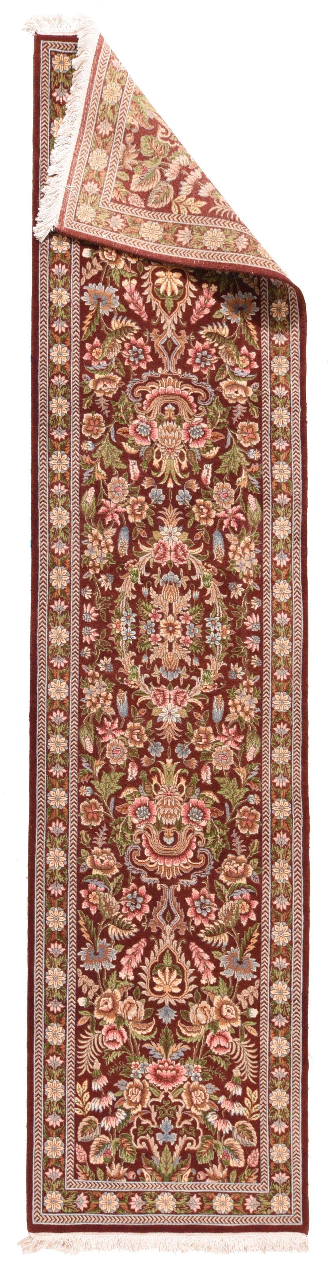 Kashan Runner 2'8'' x 11'4''. Il campo di mattoni scuri è centrato da una corona floreale ellittica che racchiude una foglia, una rosetta e un grappolo di iris, con spruzzi di rose semi-realistiche, tulipani e palmette/grappoli compositi di fantasia