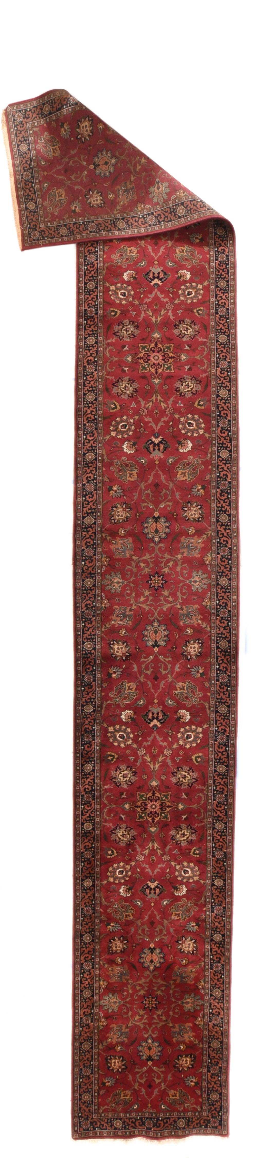 Alfombra Kashan 2'8'' x 19'9''. Este larguísimo kenare (corredor) presenta un campo rojo carmesí con palmetas inclinadas que anclan rocíos de flores, mientras que otras palmetas se unen a arabescos de acanto. También hay palmetas inclinadas de