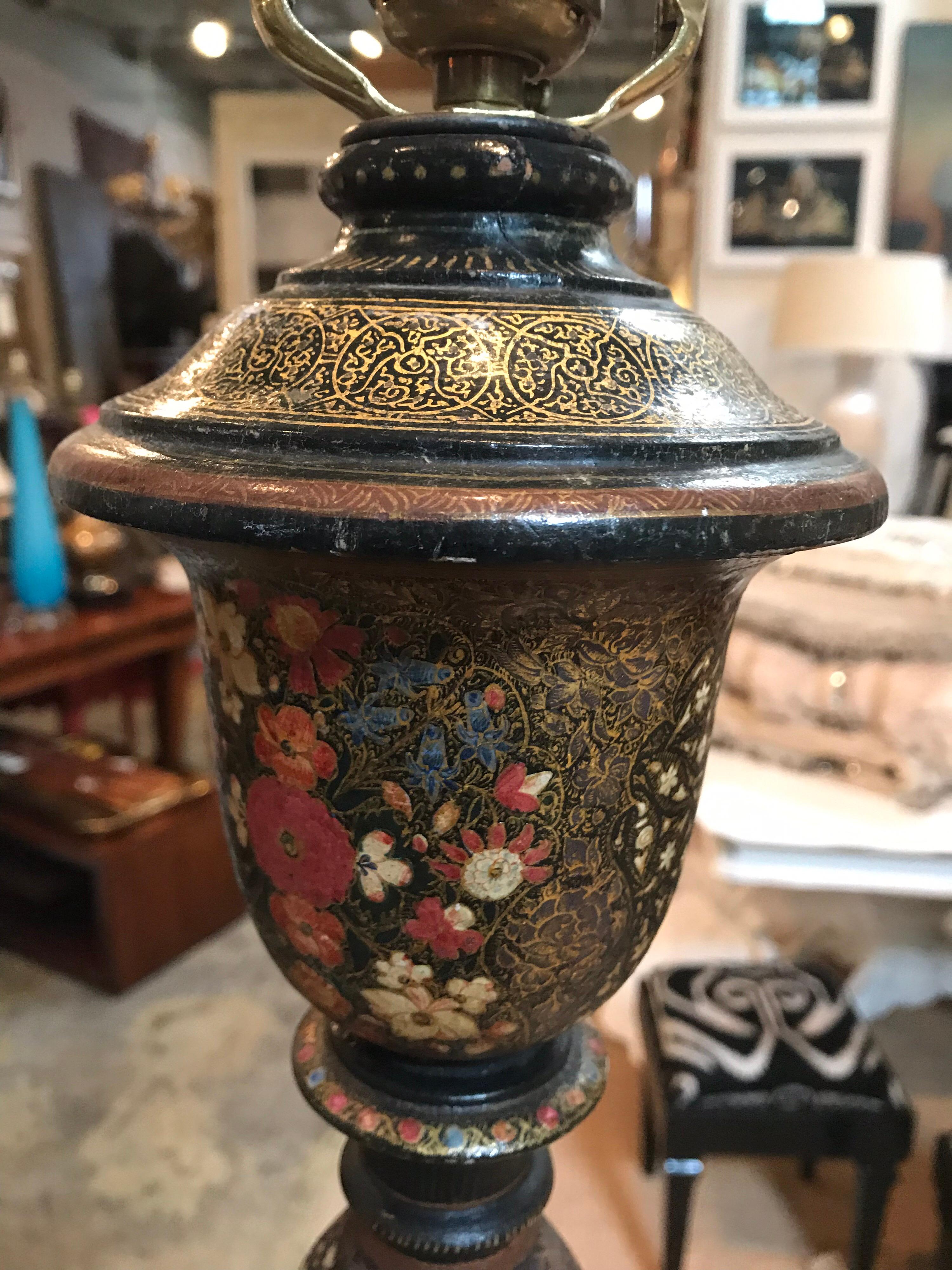 This Indian Kashmir lacquered floor lamp has a twisting stem that starts at the base and leads all the way up to the top. The background color of the Kashmir is dark while bright, colorful images of stars, flowers and patterns pop out in the