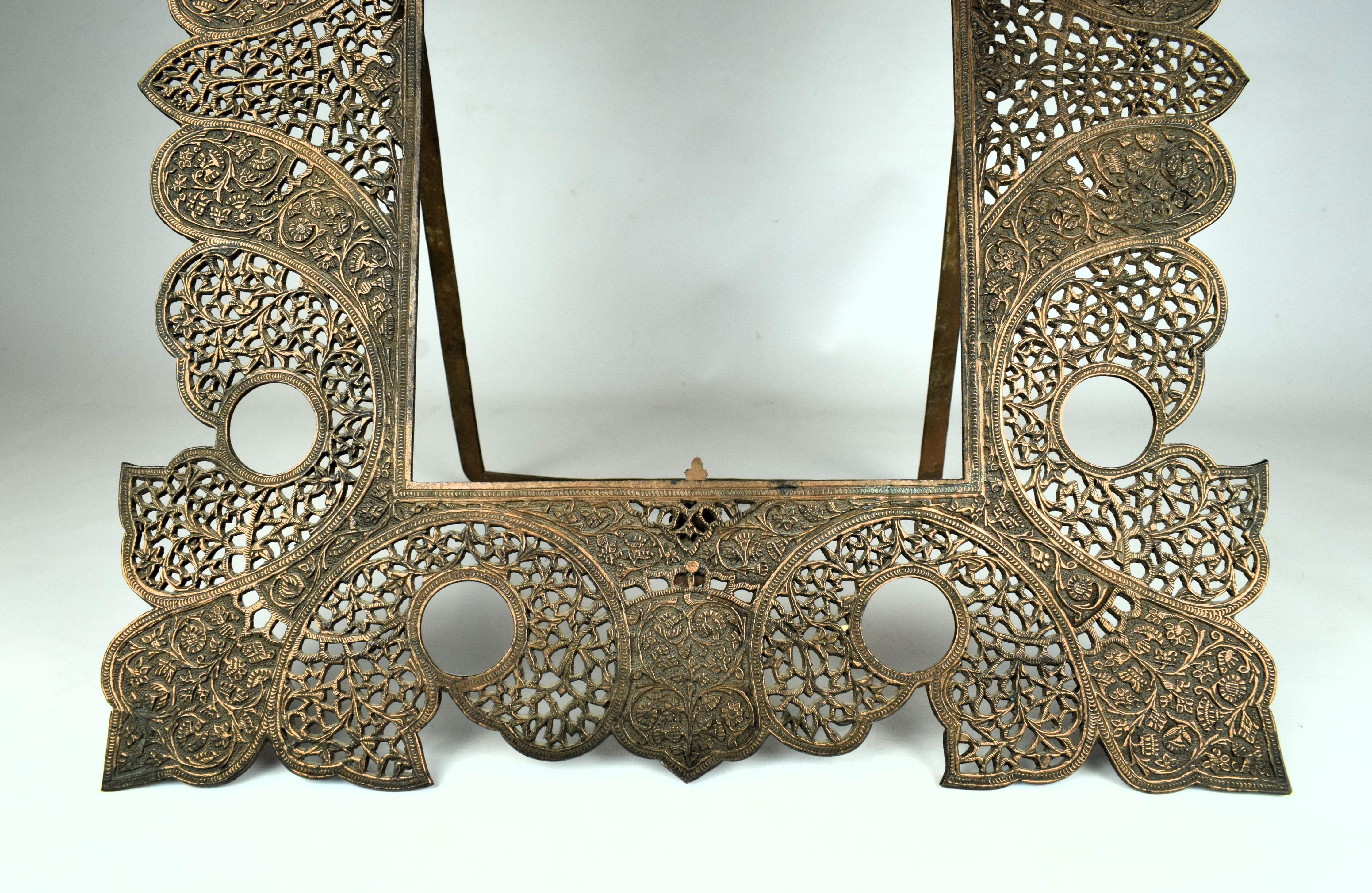 The Kashmiri copper cutwork engraved frame from the late 19th century is a masterpiece of metal artistry, showcasing the skilled craftsmanship that has been passed down through generations. The frame is crafted from high-quality copper, providing a