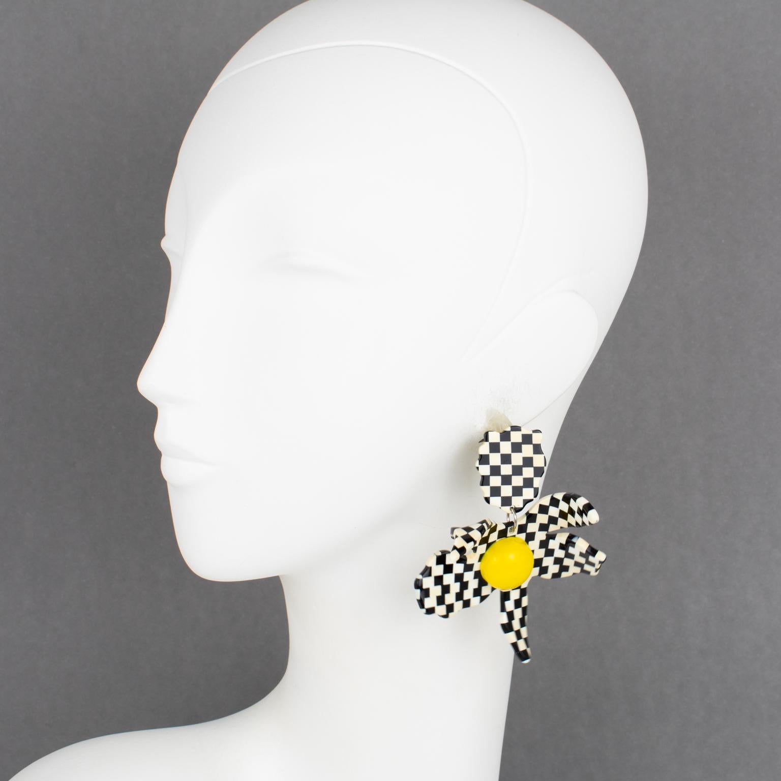 Harriet Bauknight for Kaso diseñó estos impresionantes pendientes perforados de Lucite. Presentan una flor gigante dimensional con un diseño de damero en blanco y negro y un centro de corazón amarillo de media cuenta. Como todas las piezas