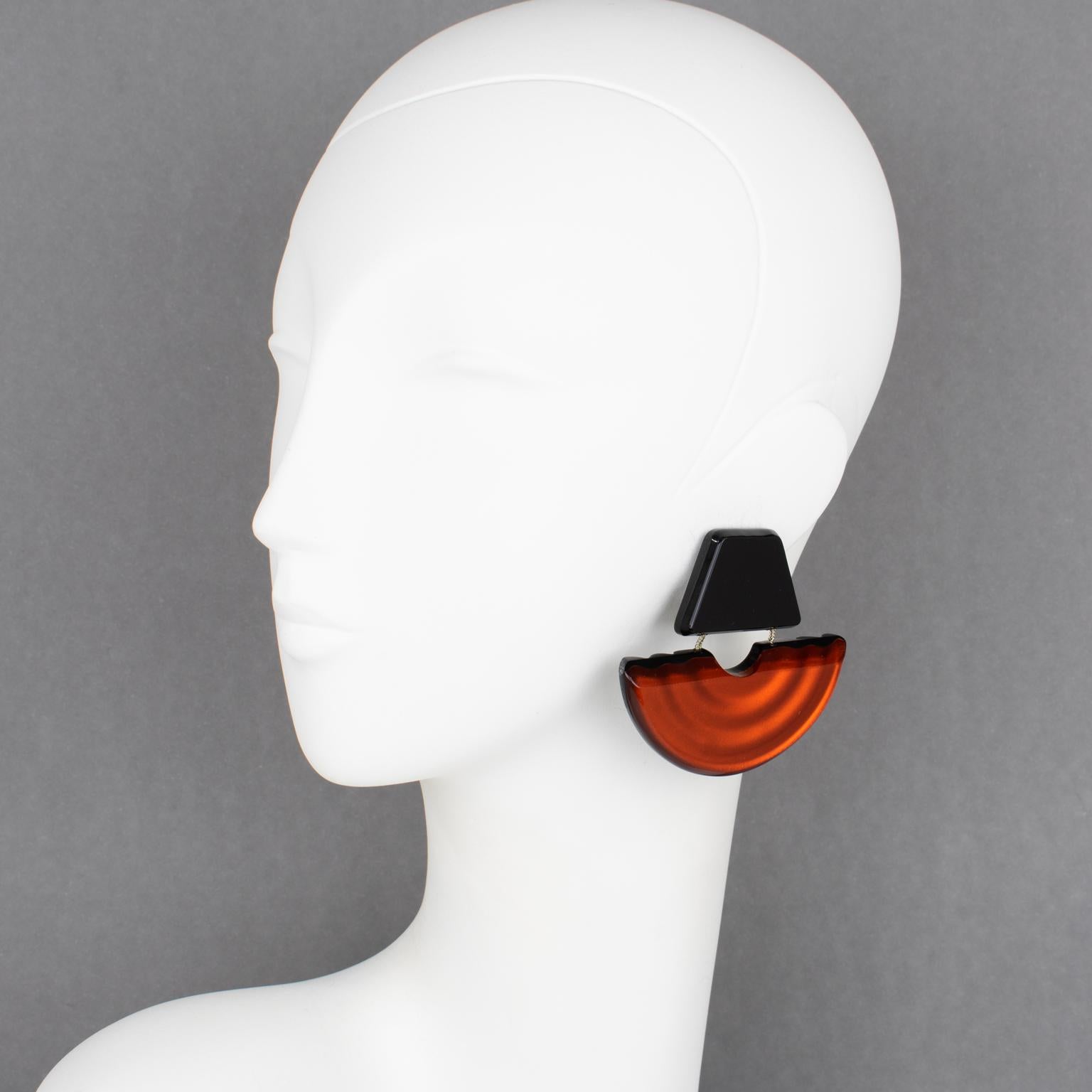 Harriet Bauknight for Kaso designed these gorgeous Lucite clip-on earrings. The geometric dangling shape features a giant fan with pearlized inclusions and large beveling. The elements are linked together with silver-tone metal chains. The burnt