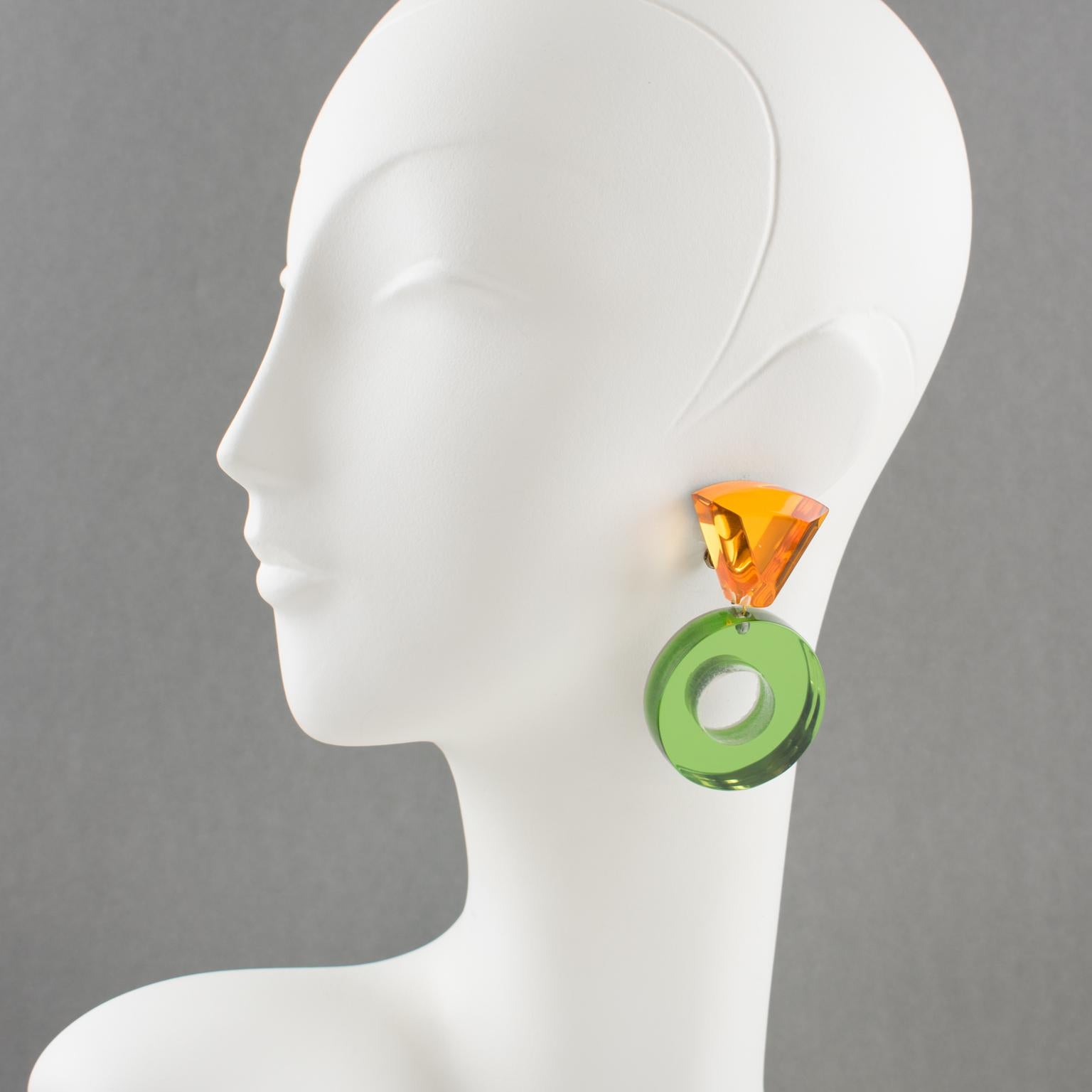 Harriet Bauknigt designed those stylish Lucite clip-on earrings for Kaso in the 1980s. The pieces boast a massive donut dangling shape with a geometric design. The mirrored textured pattern is in olive green and bright orange colors. The Kaso paper