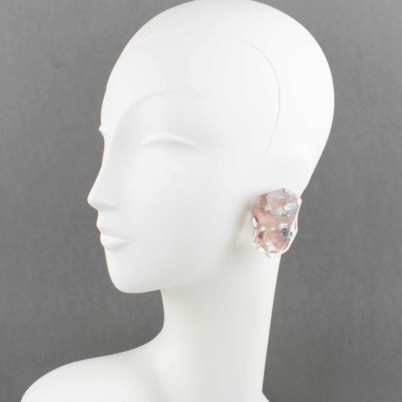 Harriet Bauknight for Kaso designed these exquisite Lucite clip-on earrings. The dimensional Lucite pebble shape has an asymmetric design and beveling. Silver and pink gold colors foil inclusions are set in the clear Lucite. The Kaso paper sticker