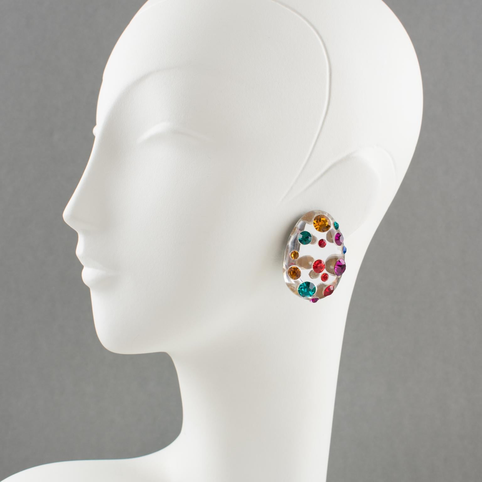 Beautiful Lucite clip-on earrings designed by Harriet Bauknight for Kaso. Features a dimensional carved egg shape with a silver glitter mirror textured pattern, all paved with multicolor crystal rhinestones. Assorted colors of red, turquoise blue,