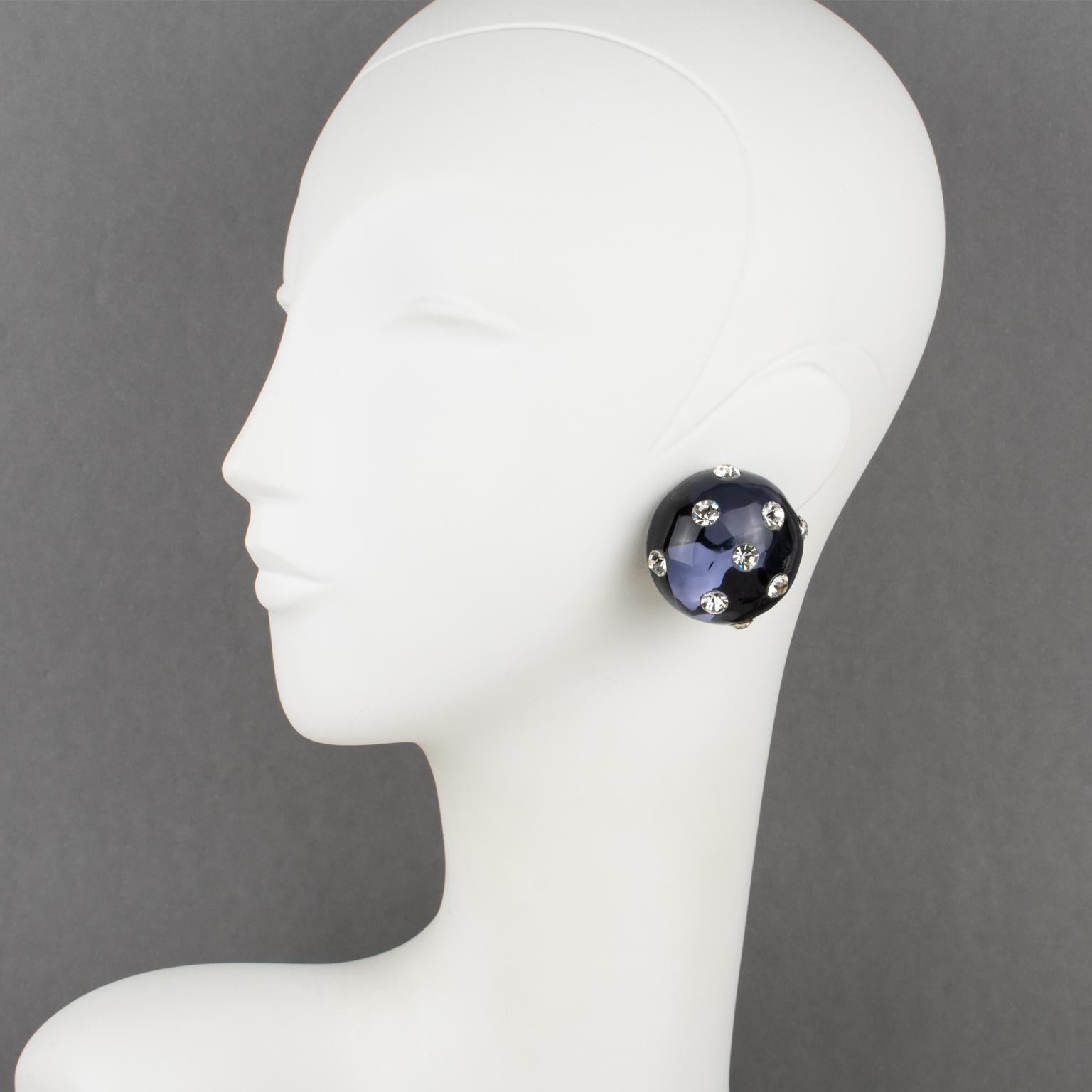 Beautiful Lucite clip-on earrings designed by Harriet Bauknight for Kaso. Features a dimensional carved round domed shape in navy blue color, all paved with white crystal rhinestones.
The Kaso paper sticker was removed, but the gray background and