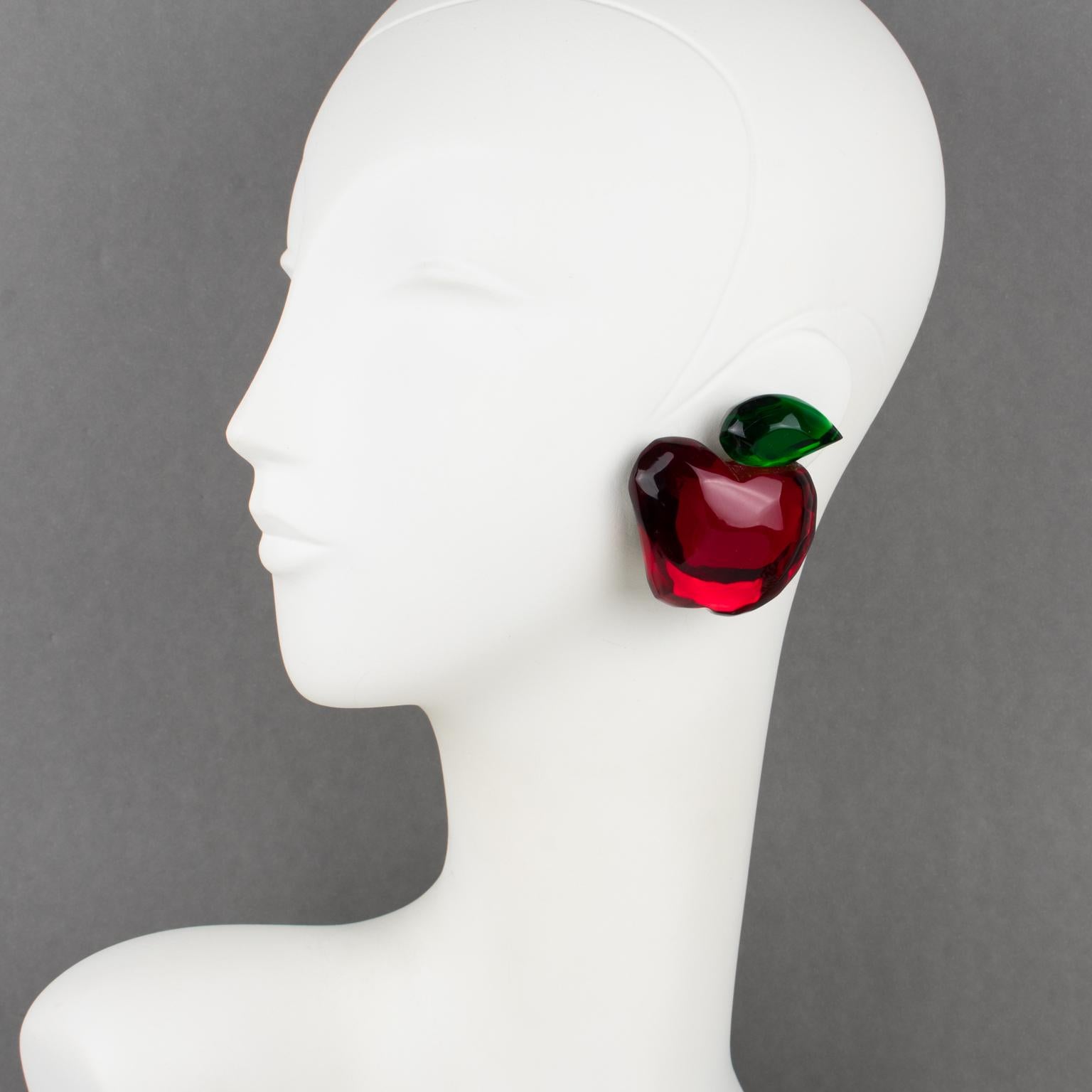 Whimsical oversized Lucite clip-on earrings designed by Harriet Bauknight for Kaso in the 1980s. They feature a dimensional apple shape, all carved with ruby red and emerald green colors and mirror-textured effects. 
The Kaso paper sticker was