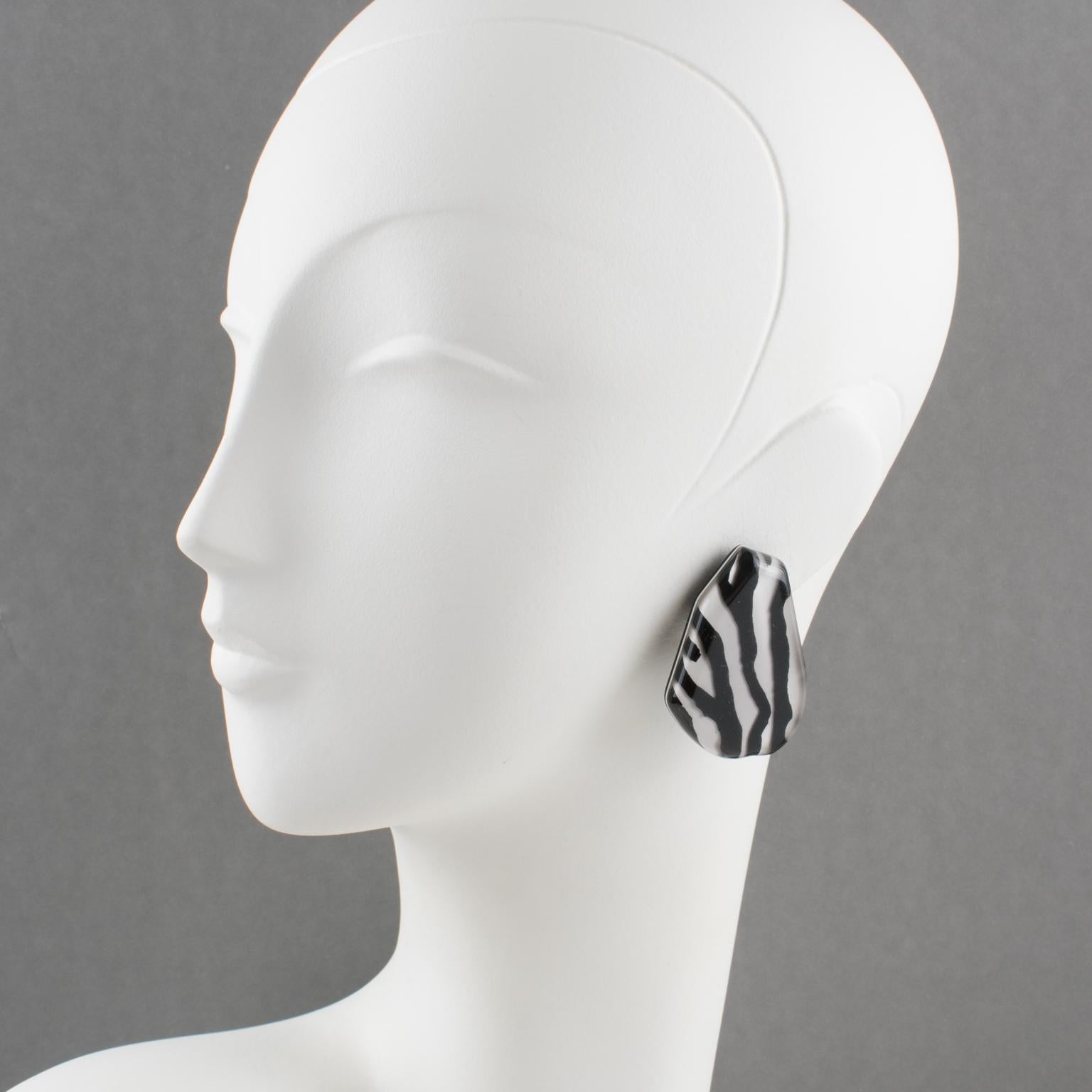 Gorgeous Lucite clip-on earrings designed by Harriet Bauknight for Kaso. Featuring a large flat free-form shape with zebra-striped pattern in black and white and beveling edges all around. 
Kaso paper sticker missing but the specific rotating clip