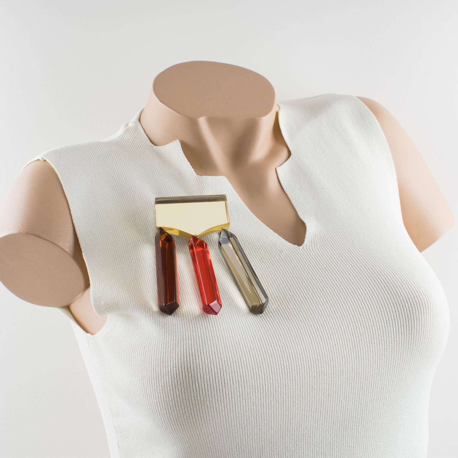 Harriet Bauknight for Kaso designed this stunning oversized Lucite pin brooch. The piece features a geometric and dimensional design with dangling long charms in assorted fall colors of yellow champagne, gold honey, burnt orange, and toffee brown. A