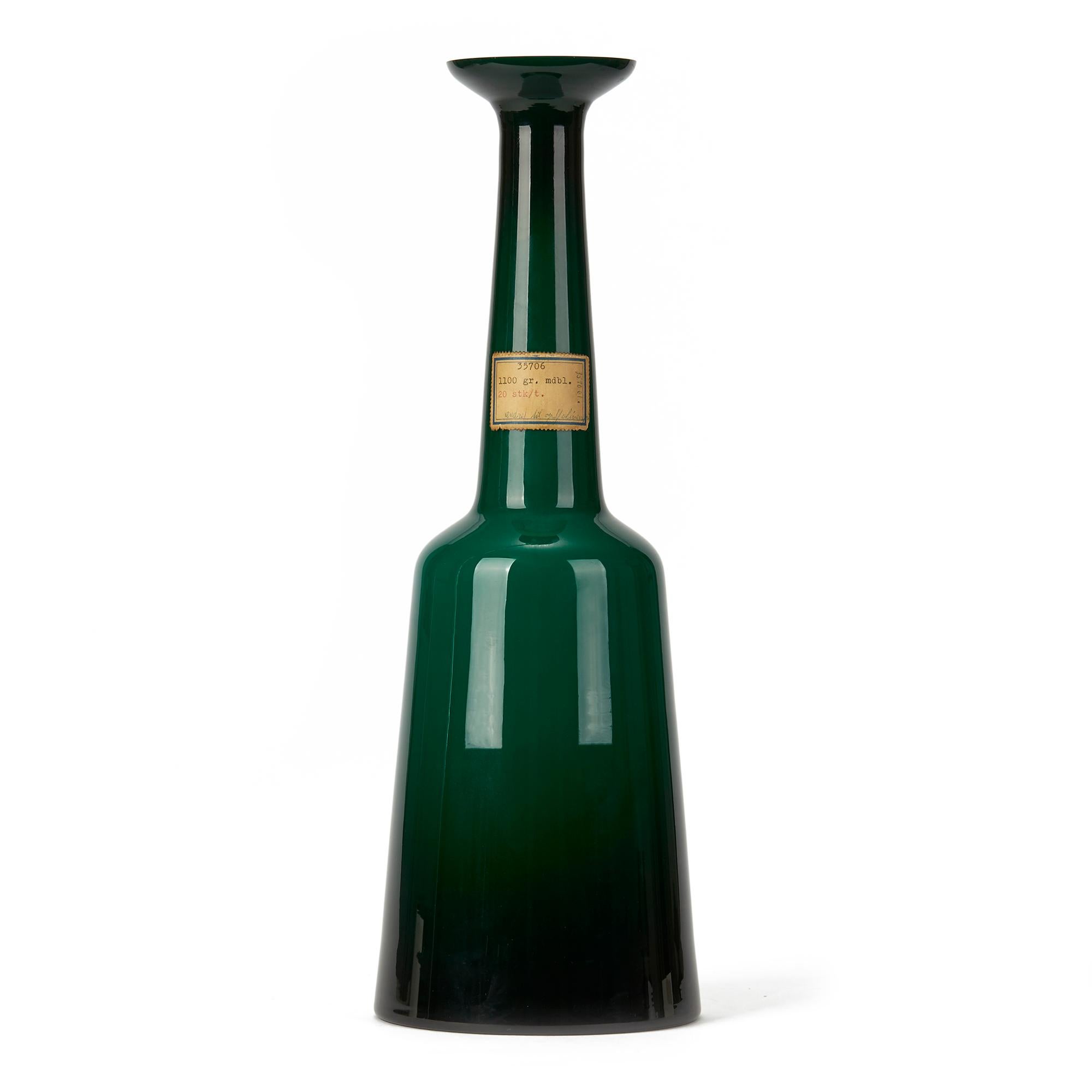 A very rare Danish Kastrup Holmegaard cased glass lamp base cased in emerald green glass with a slightly tapered base leading up to a chimney neck with flared top. The lamp base has an original drilled hole to the lower edge and retains paper labels