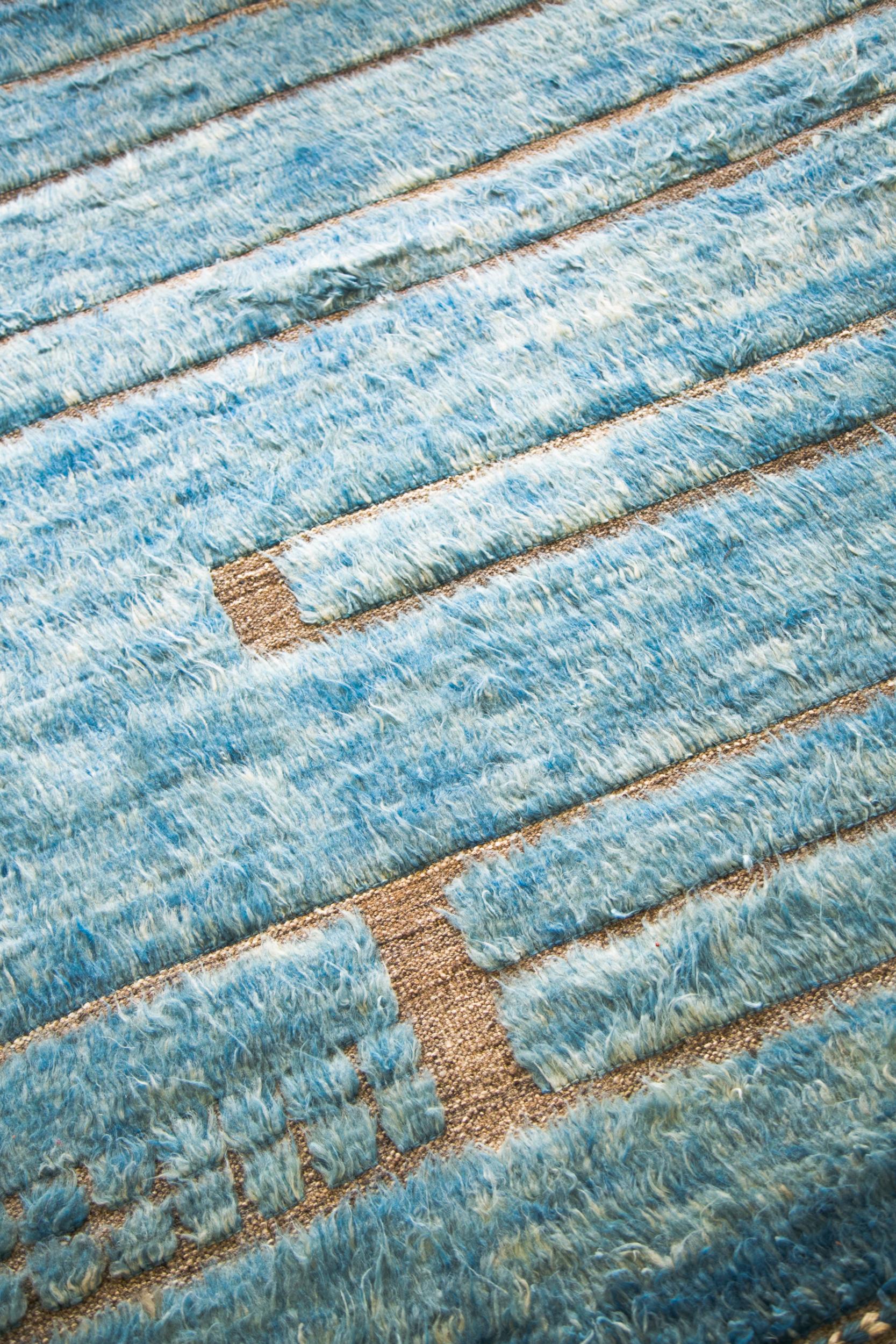 Katabatic ist handgewebt aus ozeanblauem Shag auf gemischtem naturbraunem Flachgewebe mit geprägten Details und modernen Designelementen. Katabatic wurde in Los Angeles mit viel Liebe zum Detail entworfen und ist dafür gedacht, bewohnt zu werden und