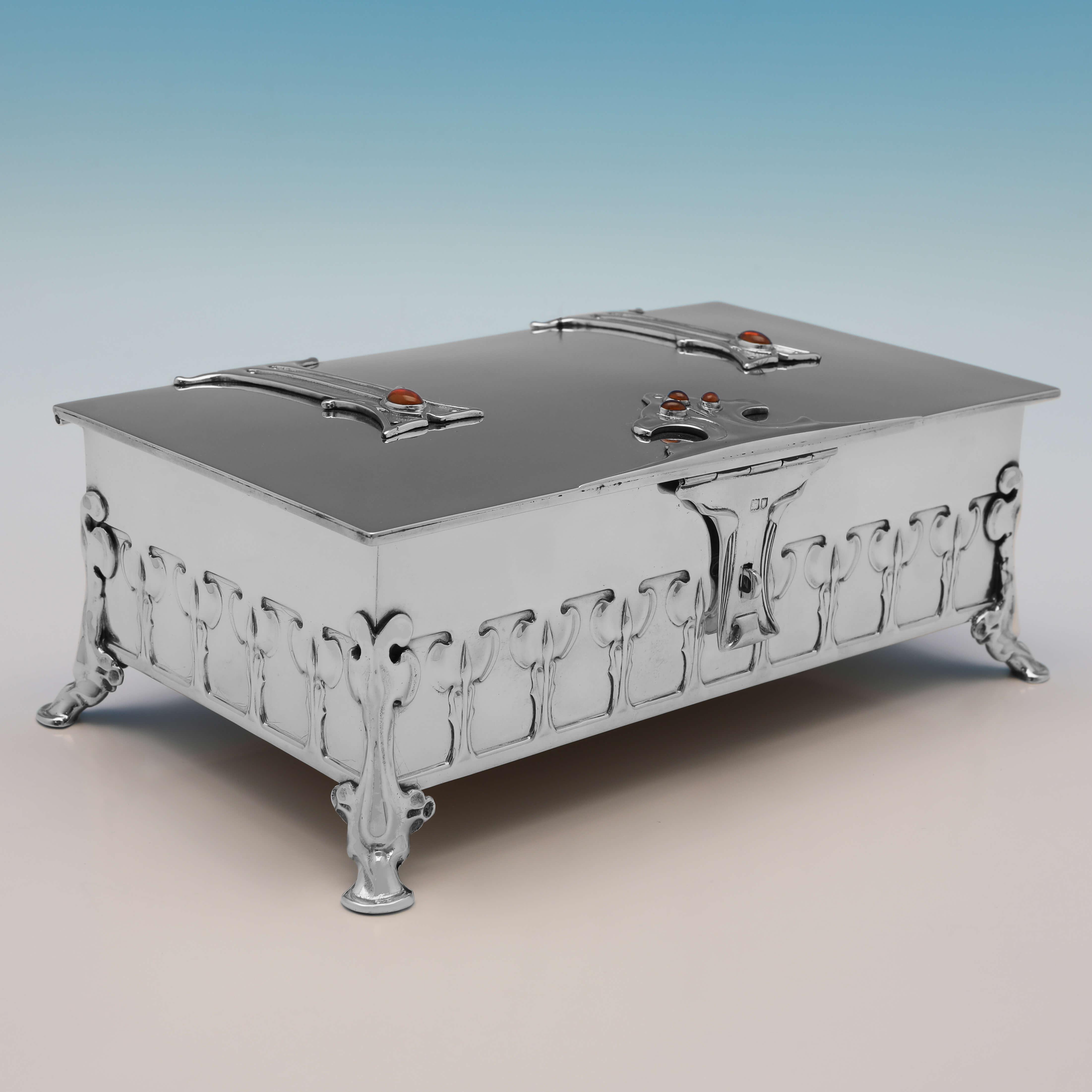 This exceptional Arts & Crafts period sterling silver casket, or box, carries hallmarks for London in 1901 by William Hutton & Sons, and was designed by Kate Harris. The casket stands on four feet, and features a repeating embossed floral pattern to