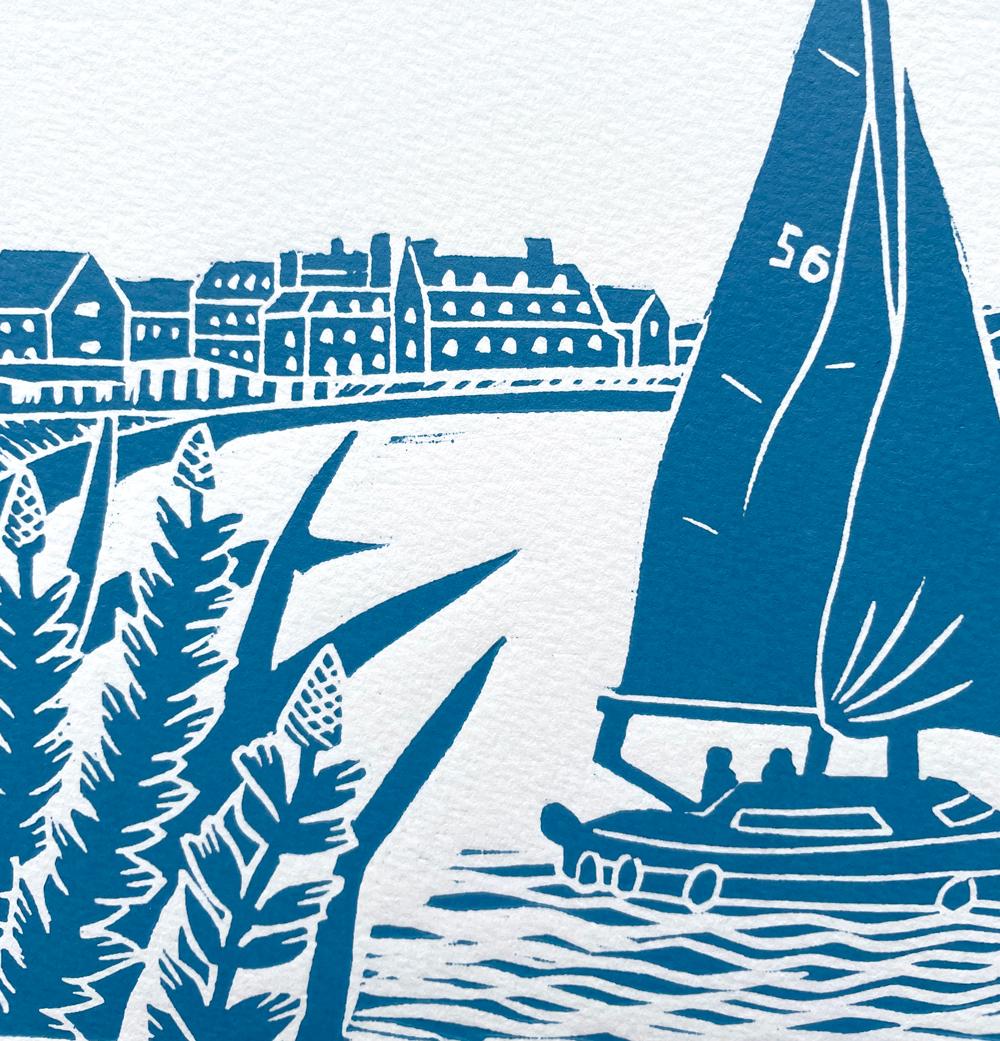 Navegando con marea alta en Blakeney, Norfolk, con el Hotel Blakeney a lo lejos, al borde del muelle. Impreso en azul náutico. Impresión en linograbado - Técnica de impresión en relieve en la que se corta linóleo, se entinta y se enrolla para crear