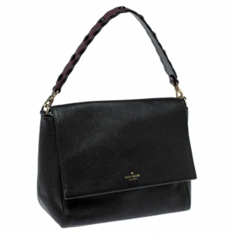 This fine-looking satchel bag is by Kate Spade. It has been crafted from quality leather and carries a classy shade of black. The bag has a front flap with the logo and it opens to a fabric-lined interior. The satchel is held by a scalloped shoulder